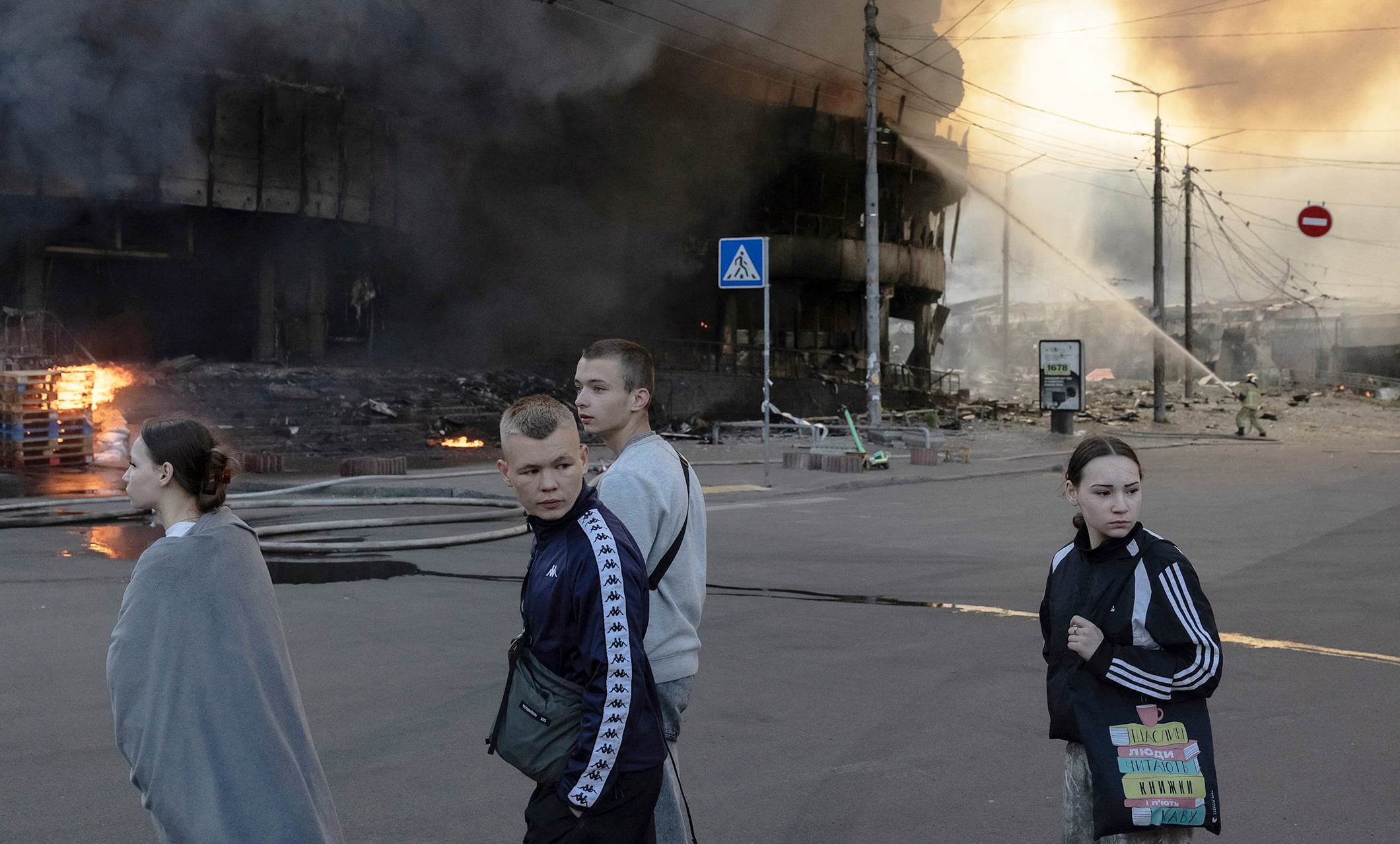 Teenagers walk past a shopping mall on fire after Russian air strikes on Kyiv last weekend.