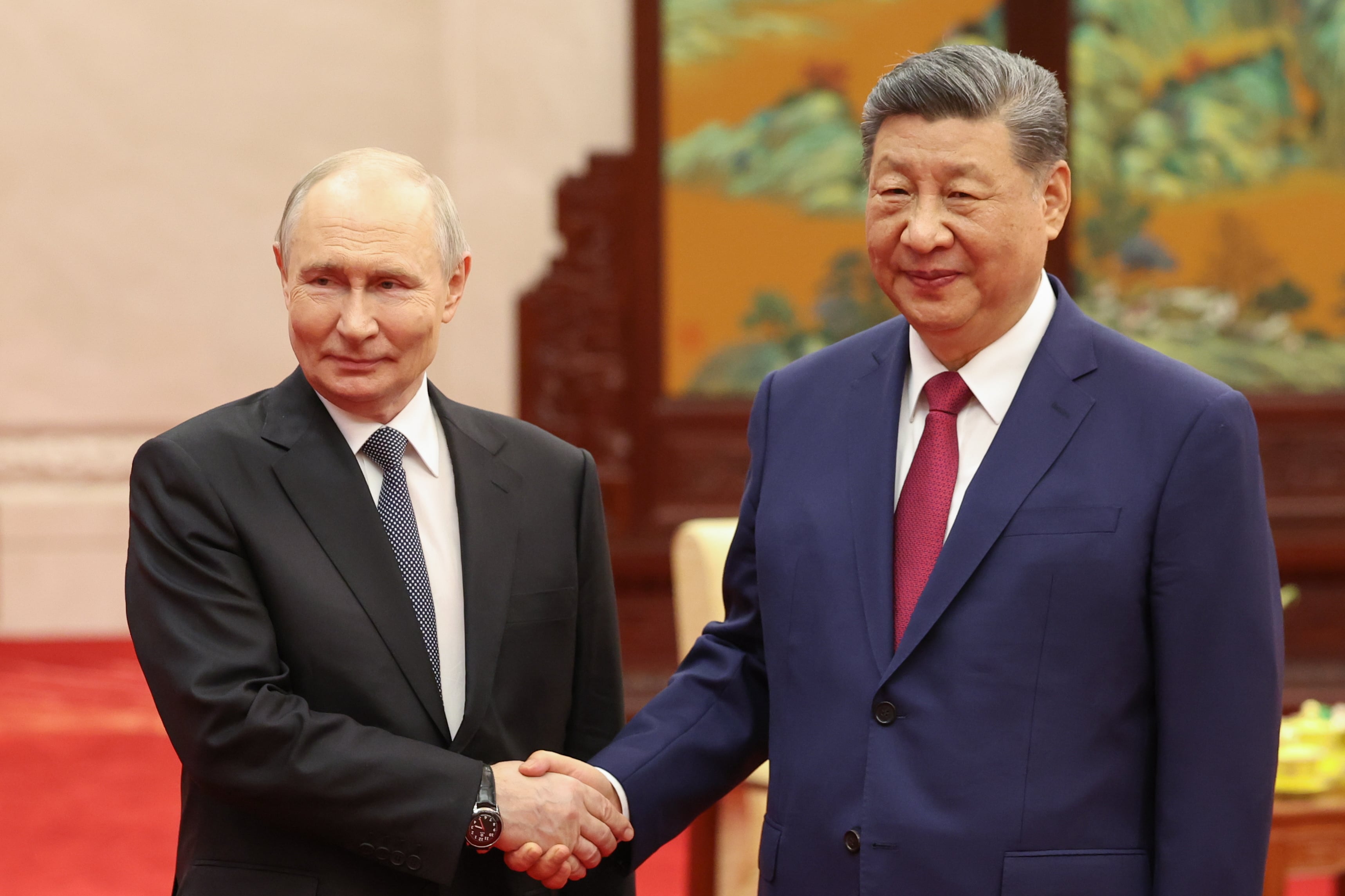 Vladimir Putin and Xi Jinping shake hands.