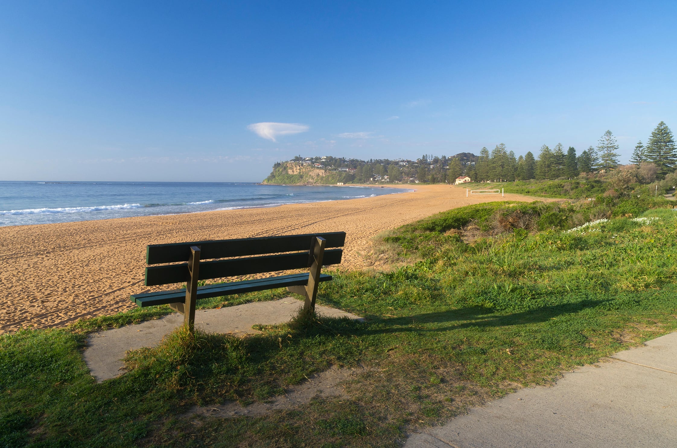 Photo of a deserted beach with park bench in foreground.