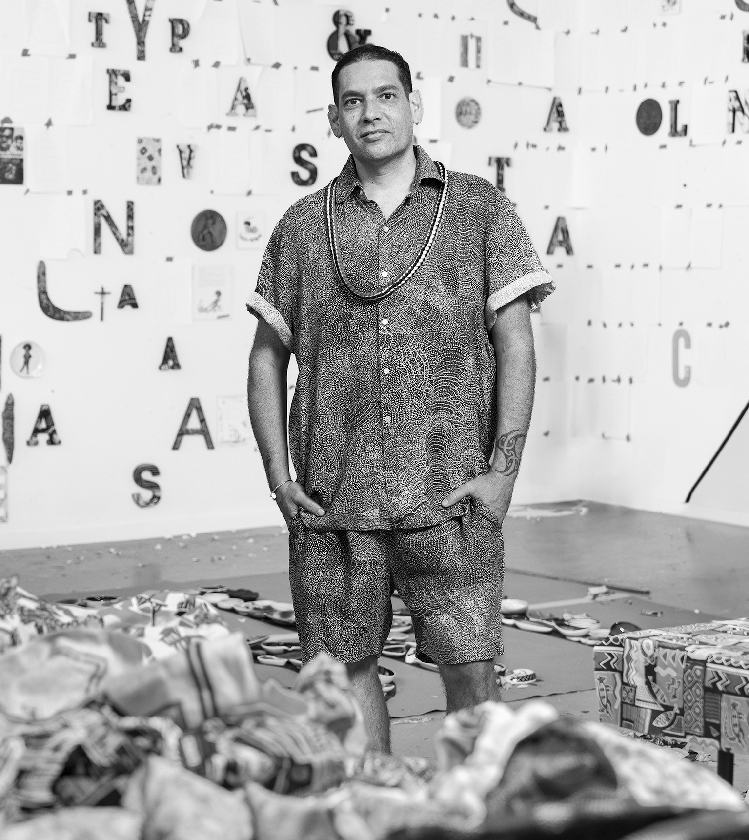 A man stands among kitsch Indigenous souvenirs.
