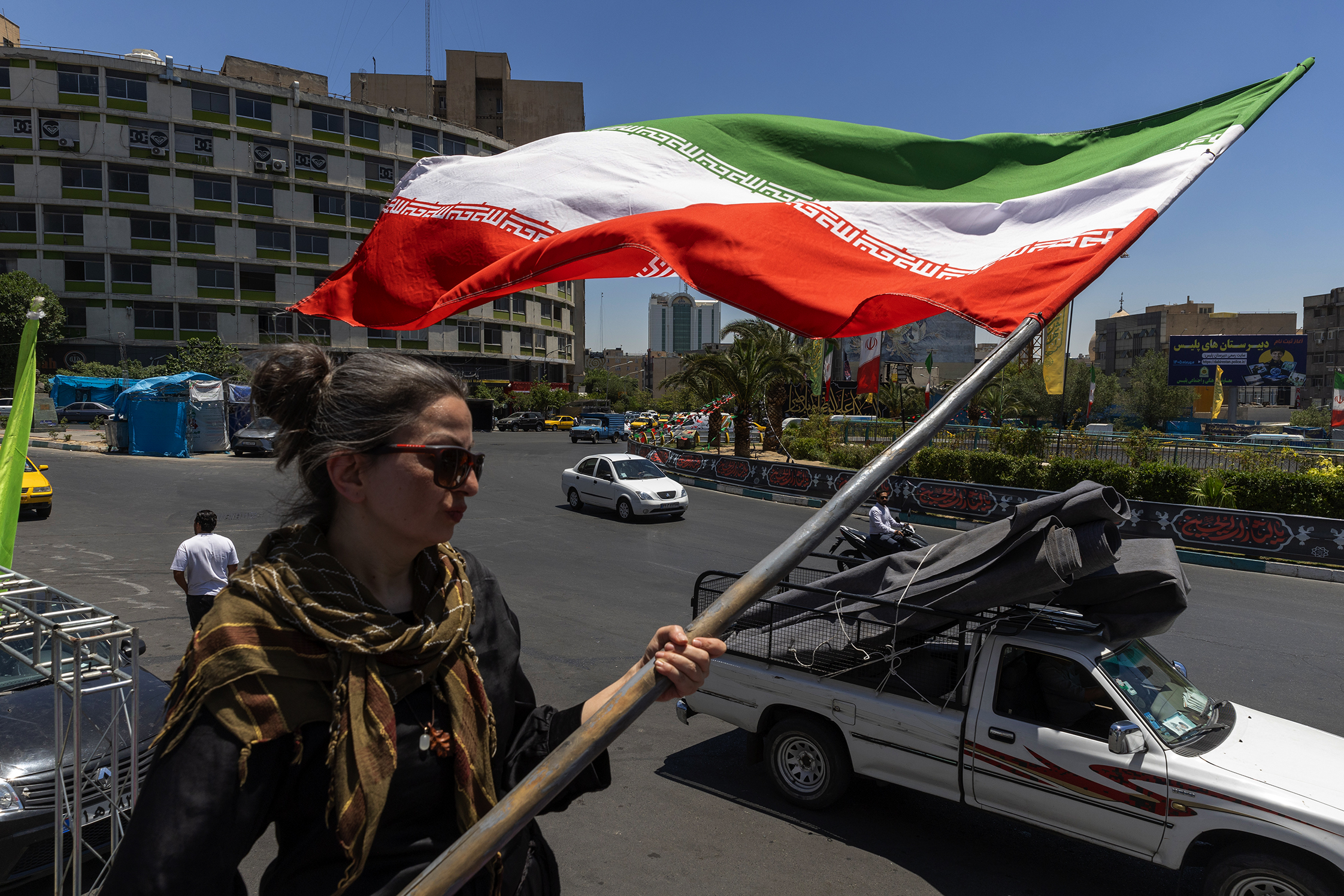 A woman waves an Iranian flag on the street of Tehran.