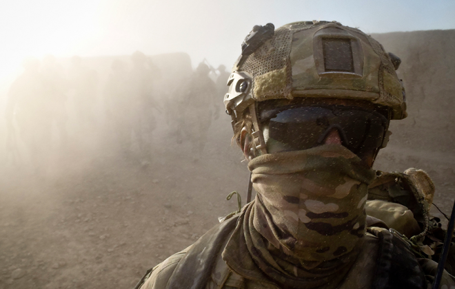 A soldier dress in camo and wearing sunglasses.