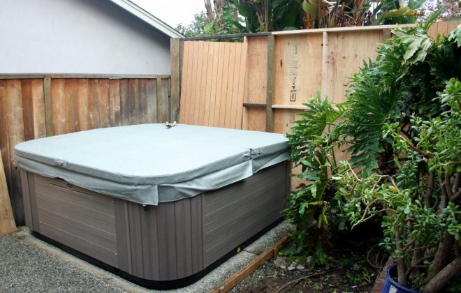 A covered spa in a small backyard.