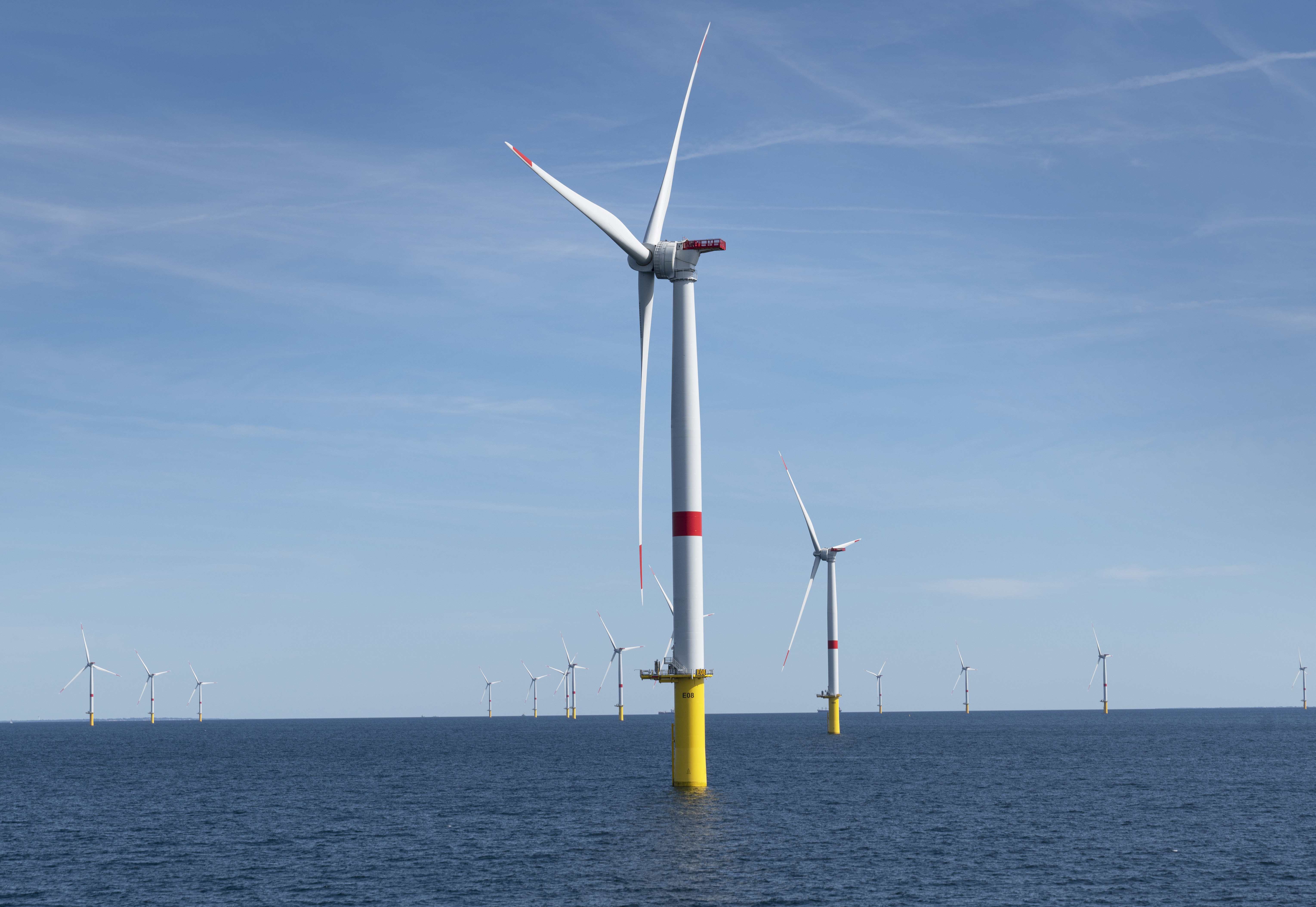An offshore wind farm under a blue sky.