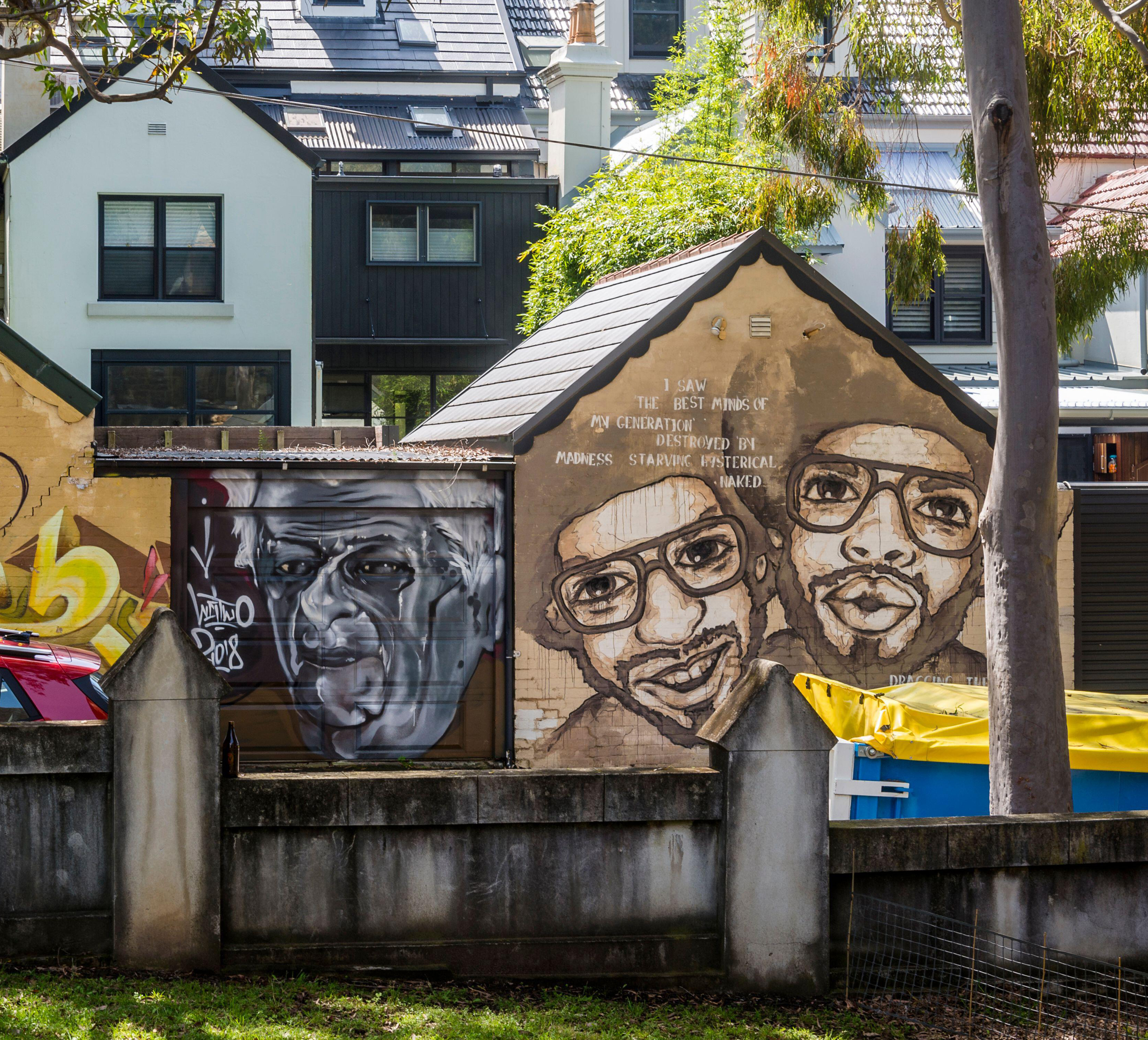 Graffiti portraits of eccentric figures on the back of a building.