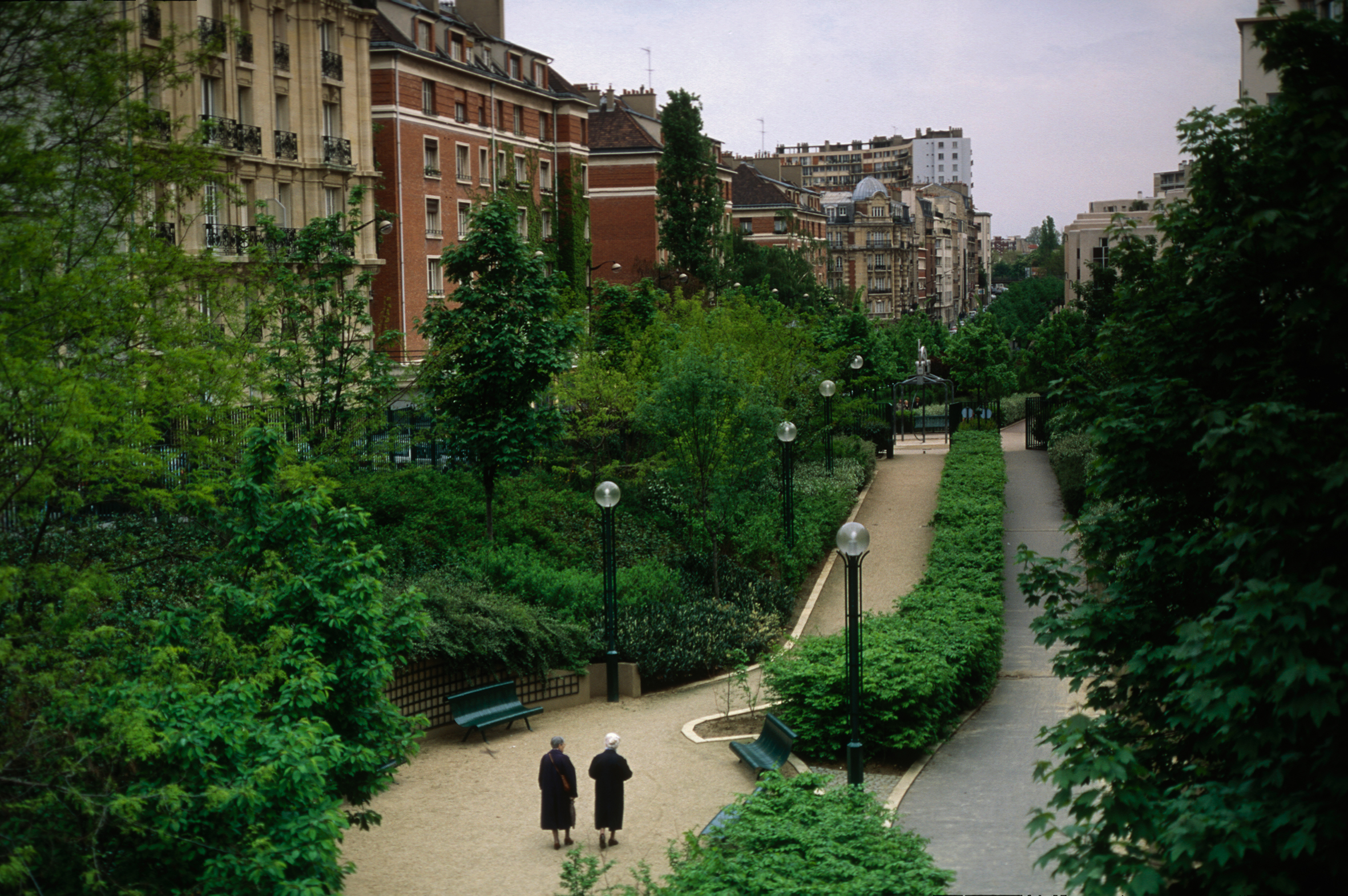 Two elderly women walk through a park in Paris.