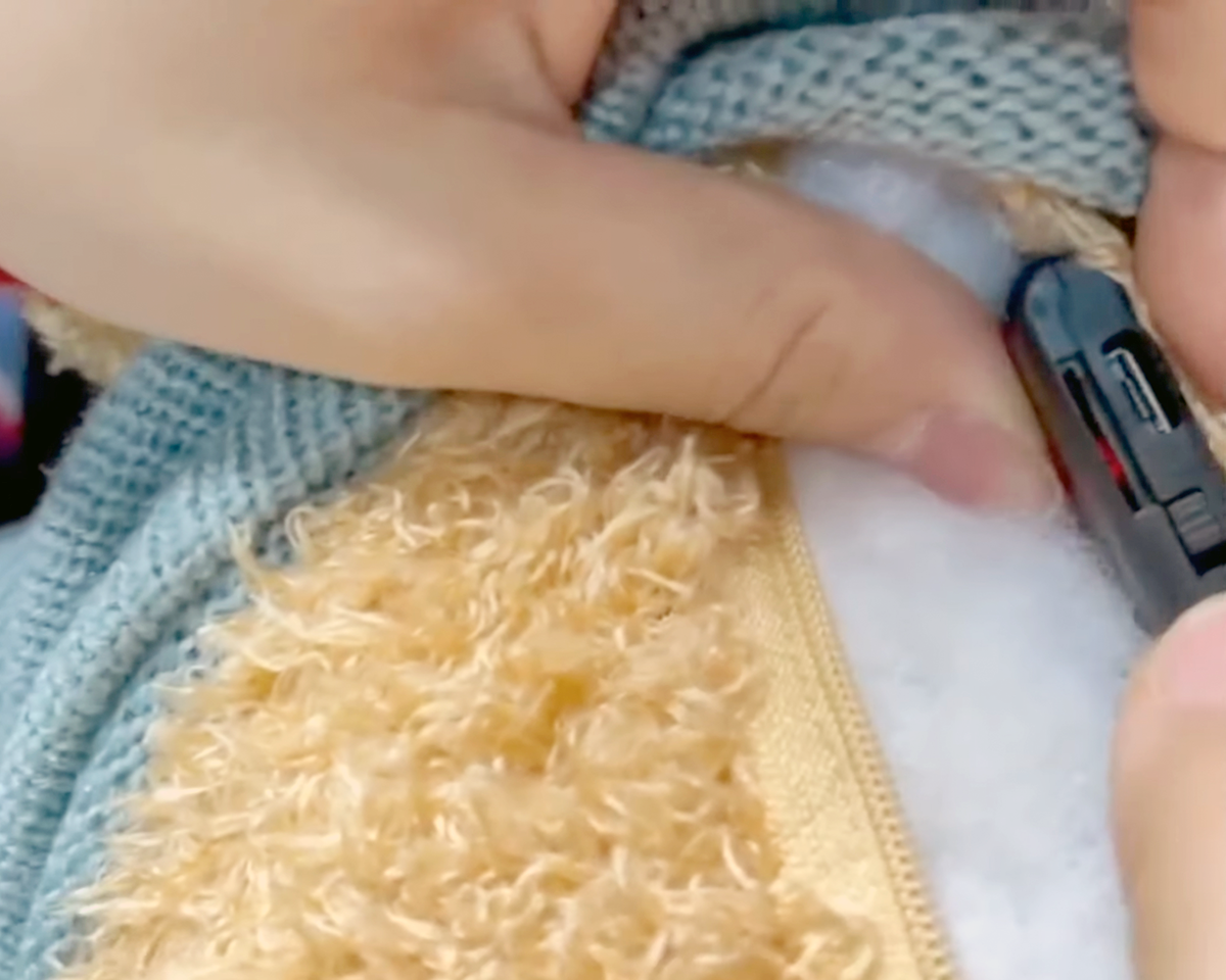 A man inserts a spyware into the back of a teddy bear.