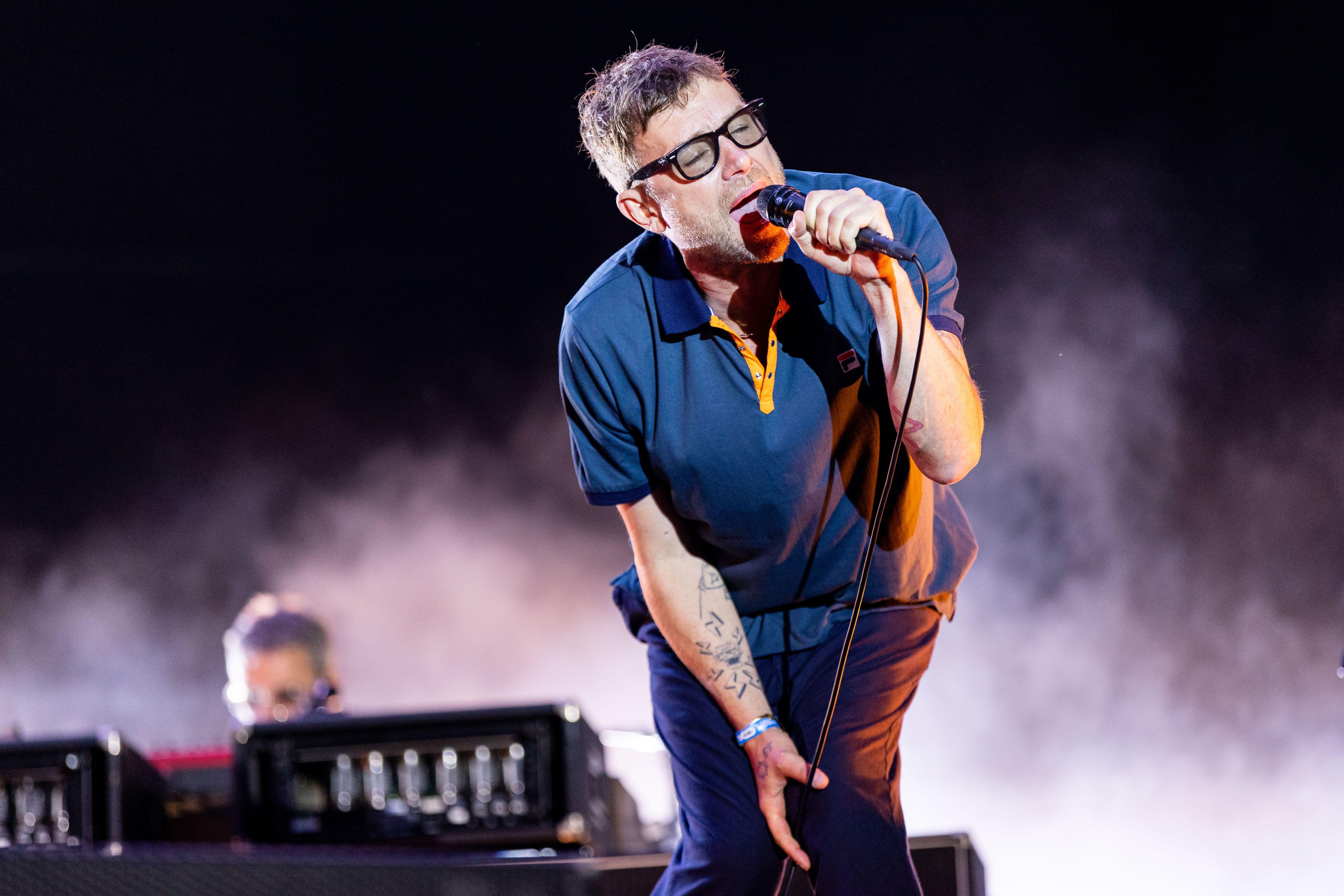 A musician performs onstage with a microphone in their hand.