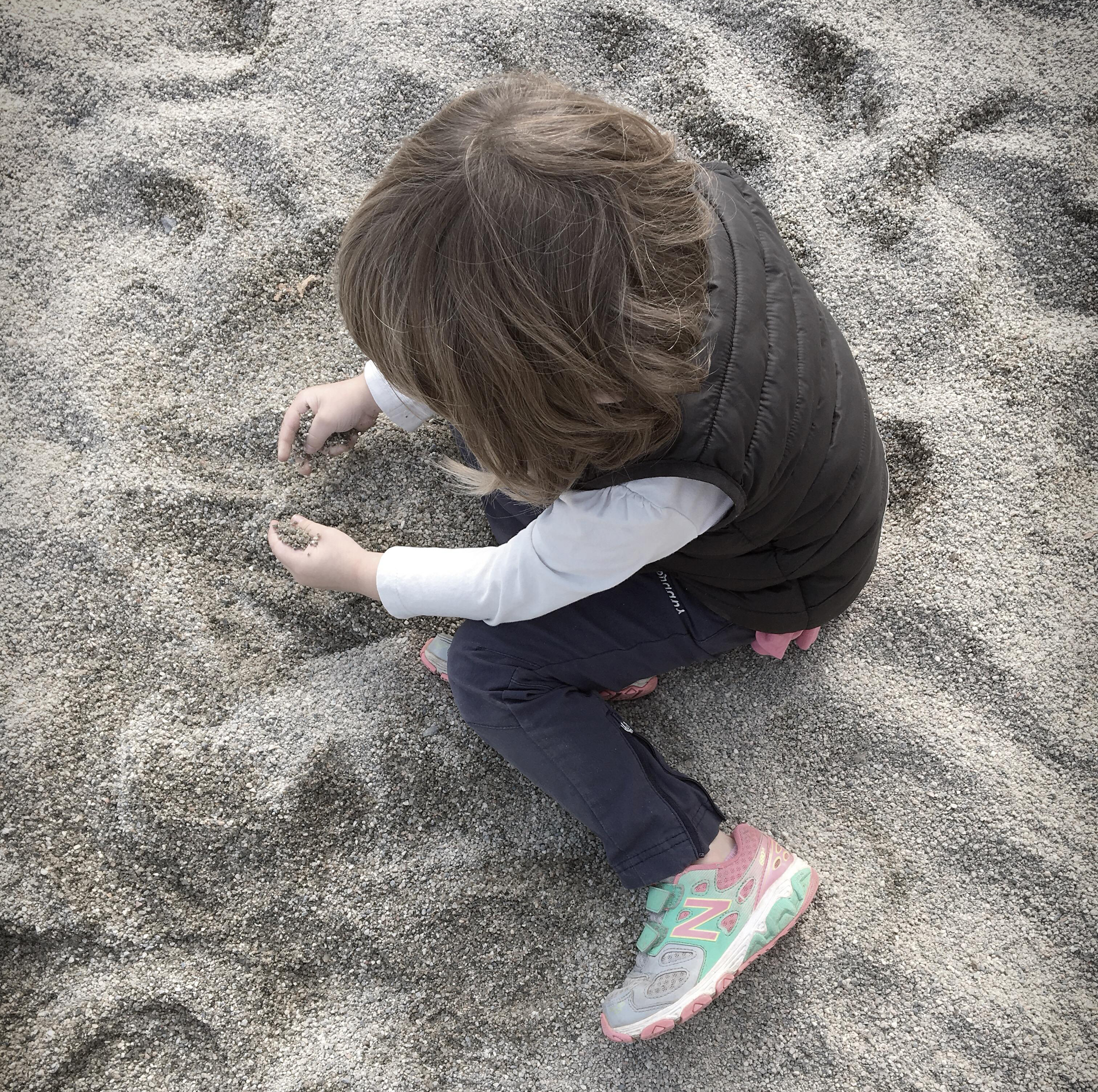 A child plays alone in a sandpit. 