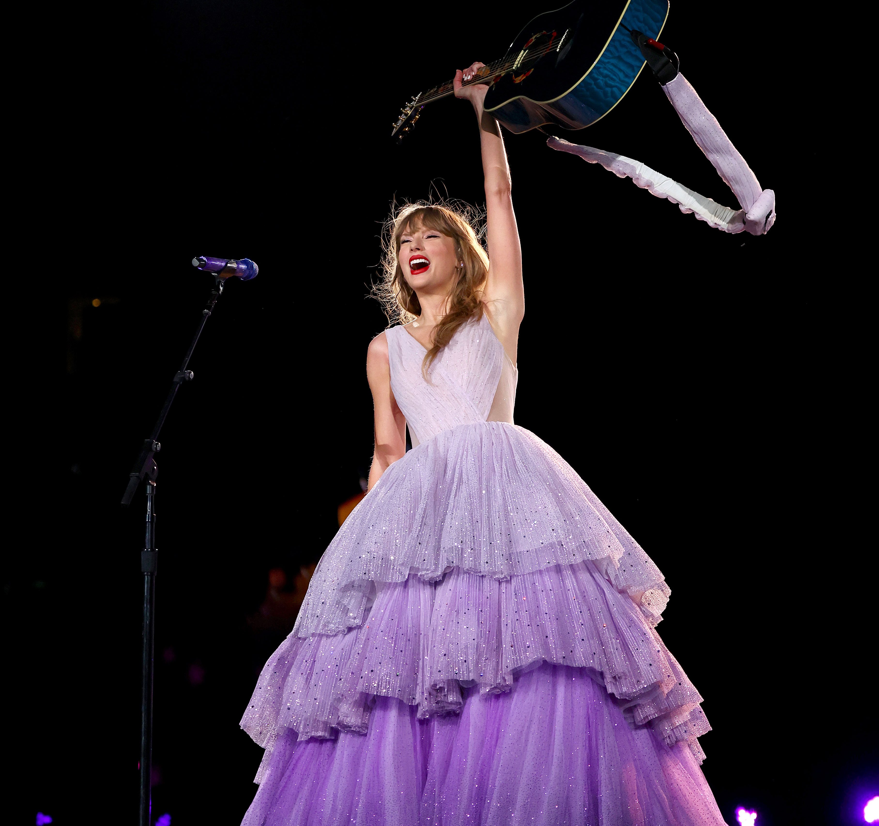 Taylor Swift wearing a purple dress on stage.