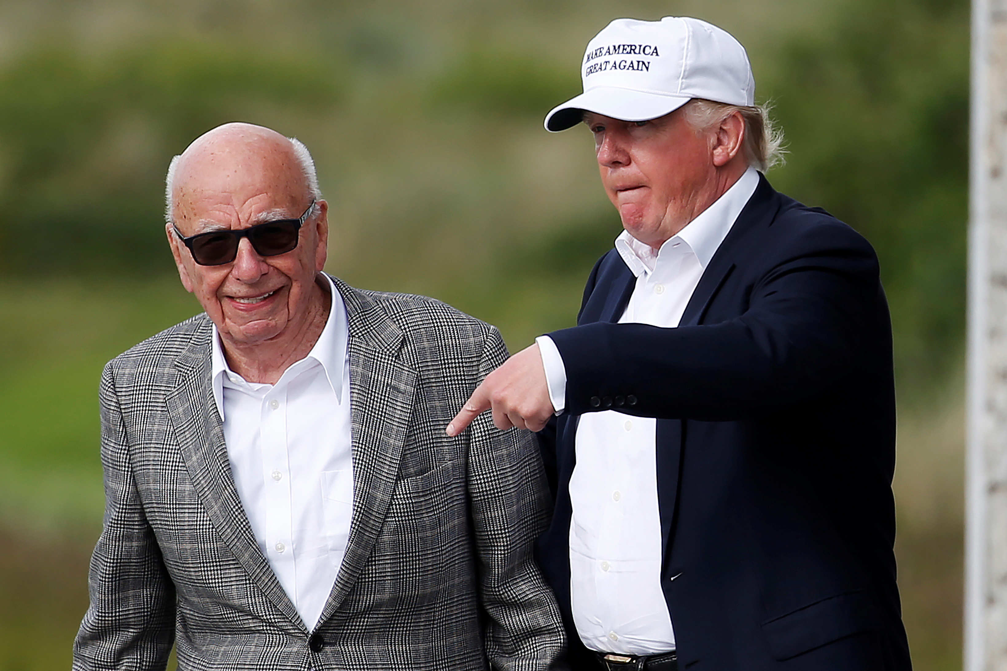 Rupert Murdoch and Donald Trump walk beside one another.