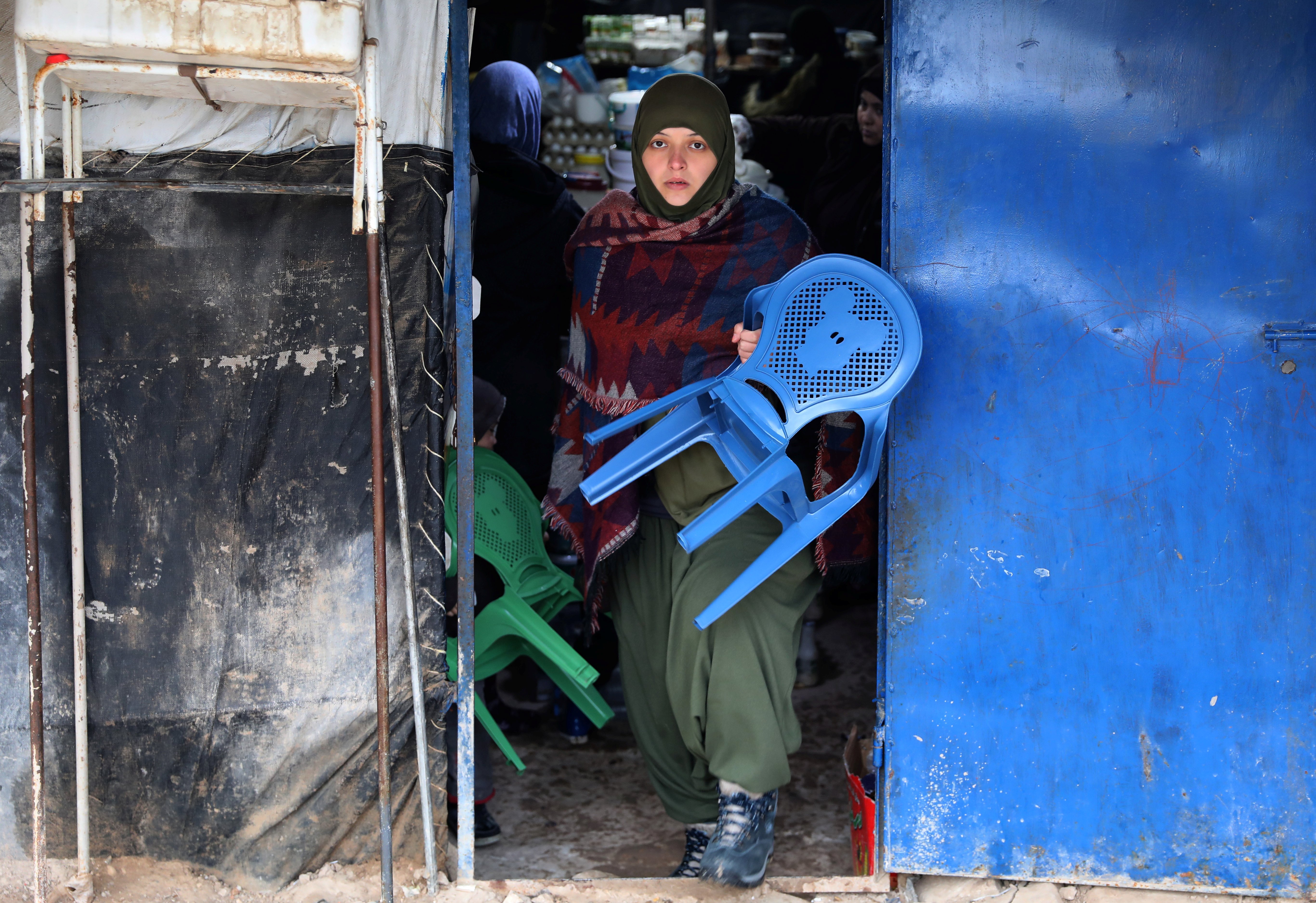 A woman carries a chair in the Al Roj camp in Syria. 