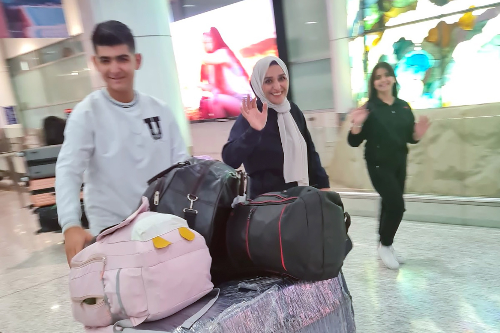 Nariman Saifaddin Alyousif (centre) with her children Mammo (left) and Hevi (right), arriving at Sydney Kingsford Smith Airport in November 2022. 
