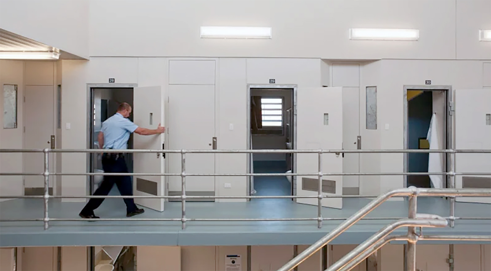 A prison guard opens a cell door.