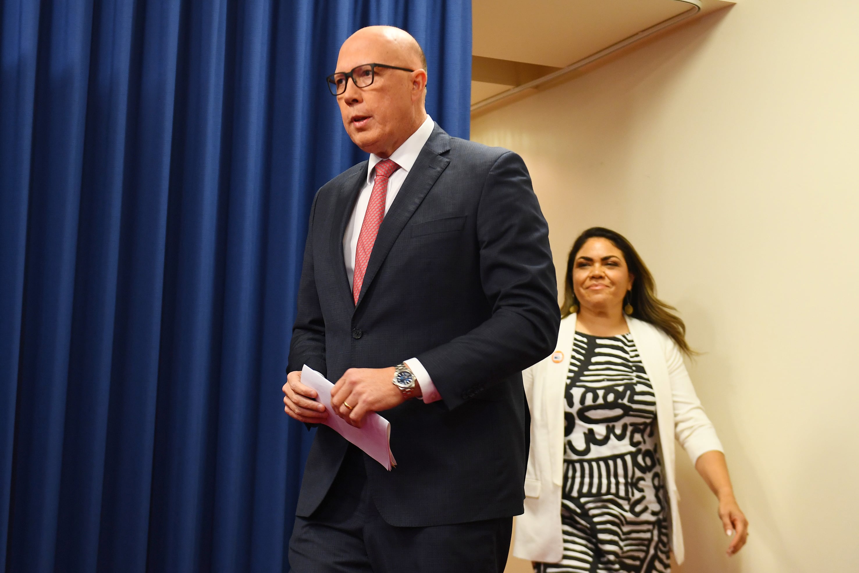 Peter Dutton and Jacinta Nampijinpa Price walk around a blue curtain.
