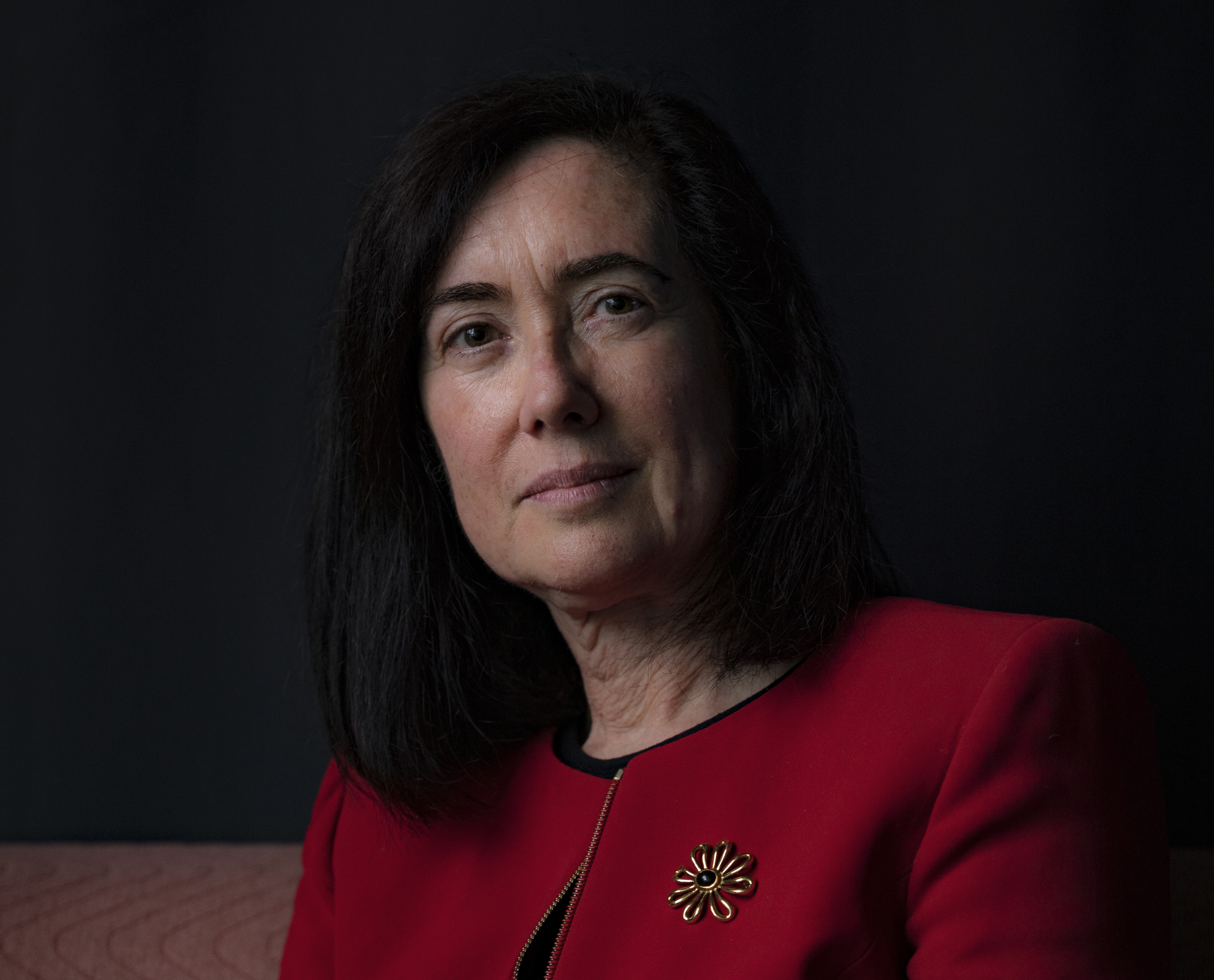 A portrait photograph of a woman with black hair and dressed in a red blazer.