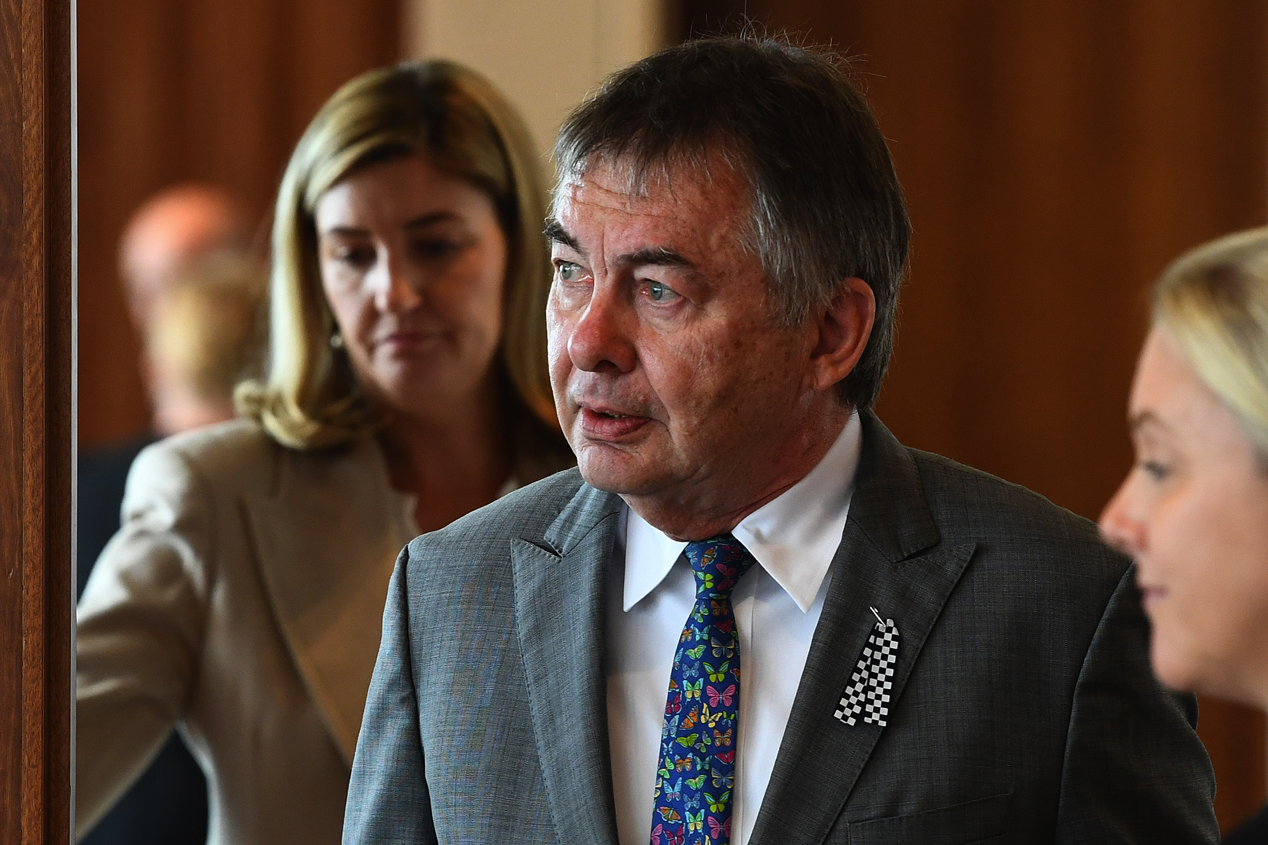An elderly man in a grey suit matched with a patterned tie. 