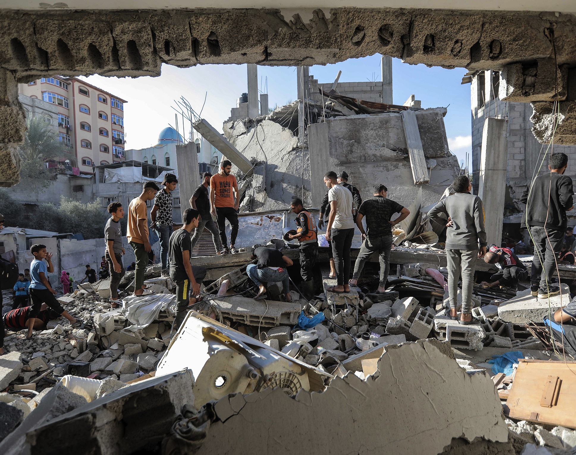 A group of men search through the debris of a fallen building.