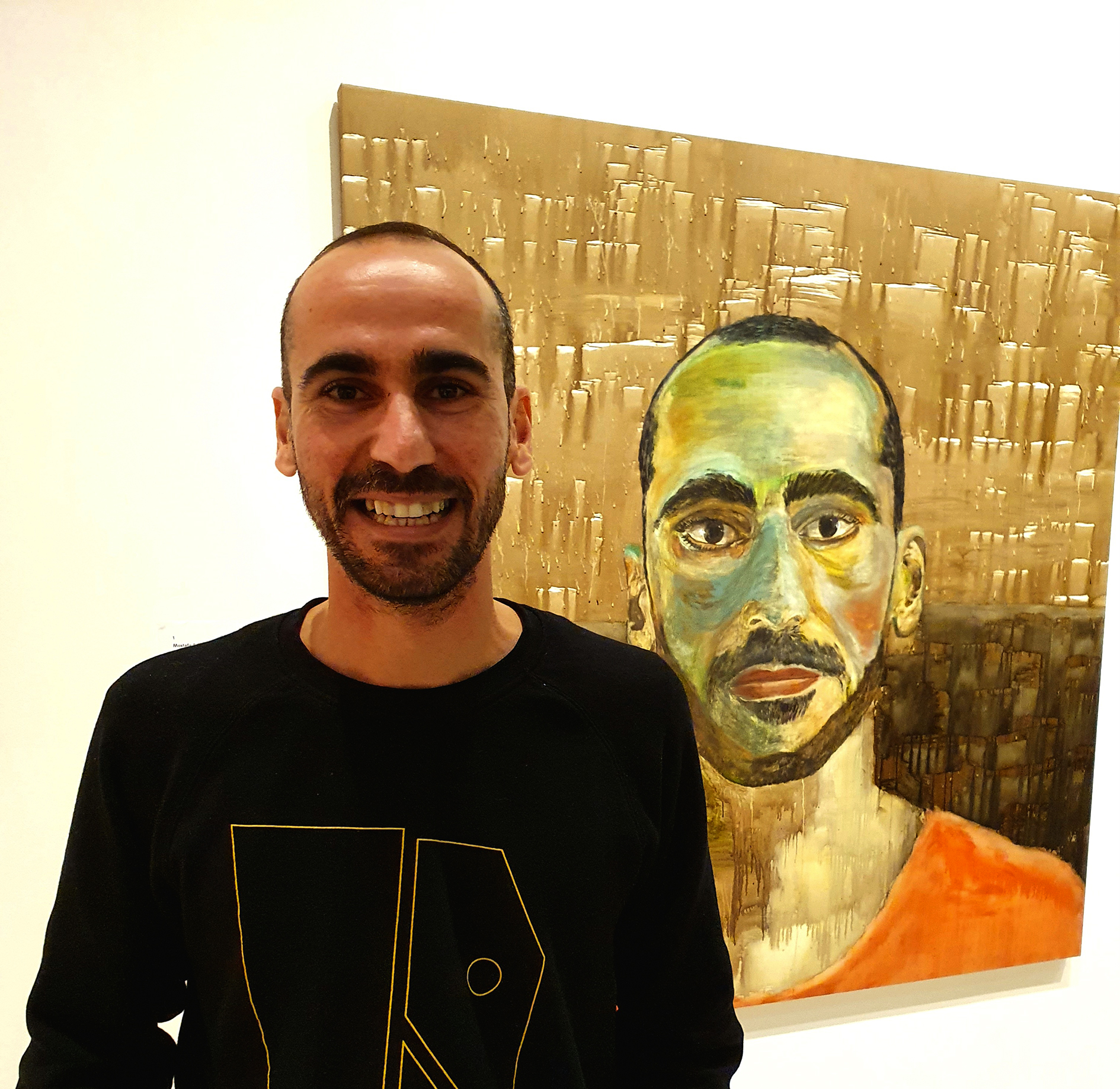 A man smiles beside his own portrait painting.