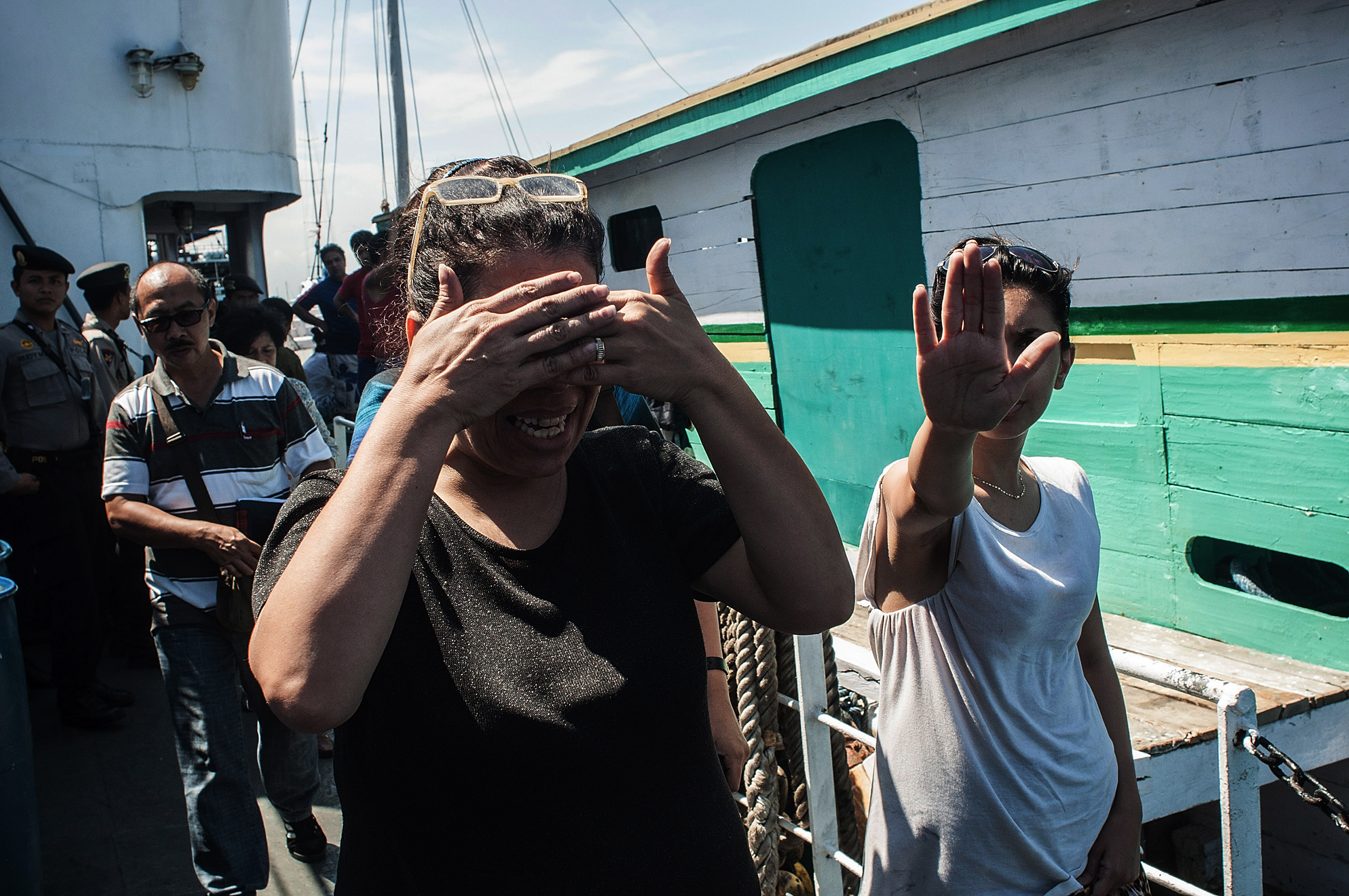 Asylum seekers covering their faces as they step off a boat.