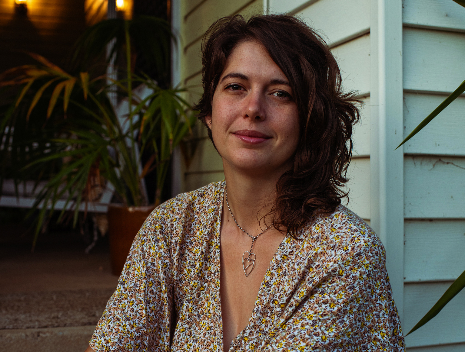 Portrait photograph of climate activist Violet CoCo. She has dark brown hair and is wearing a bright floral dress.