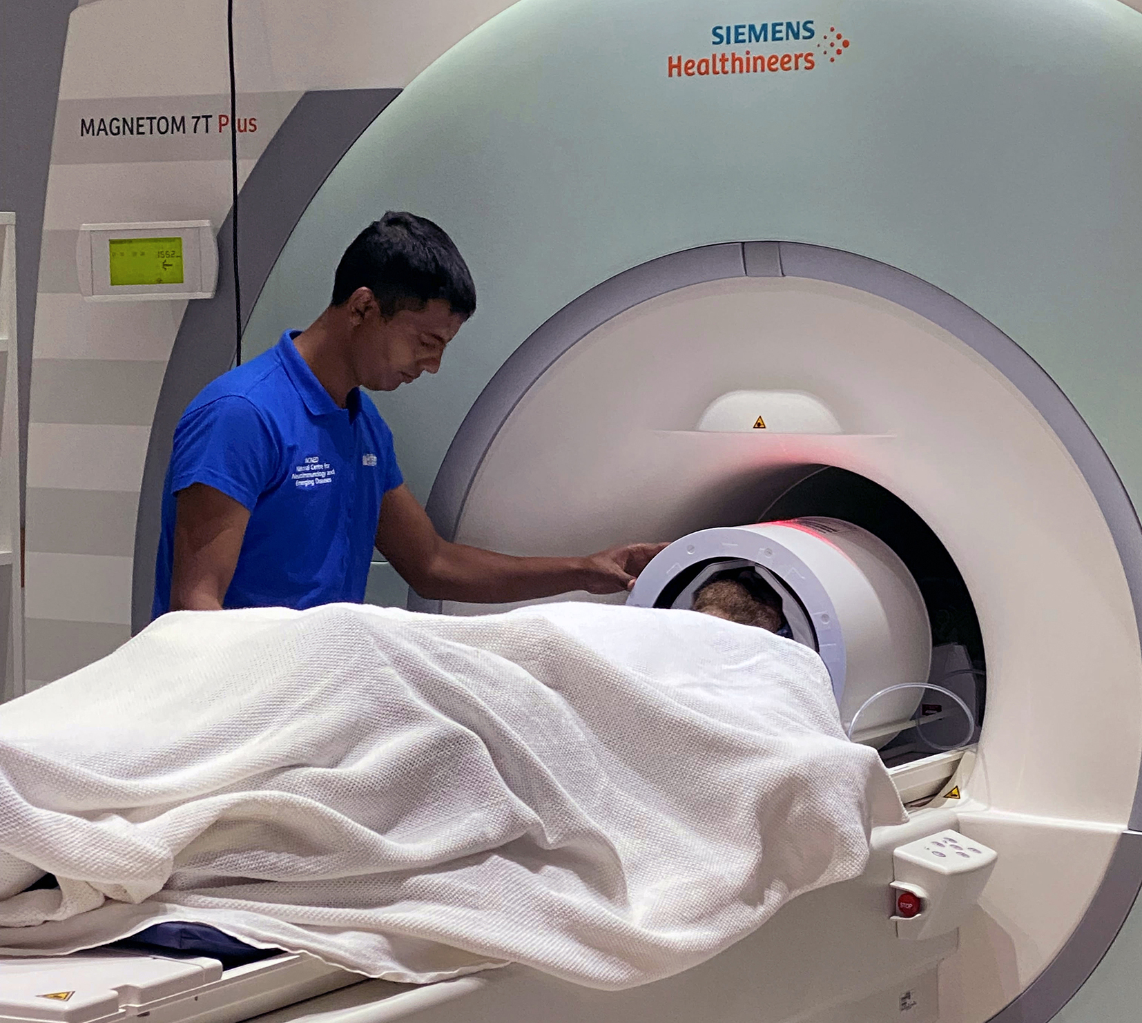 A doctor leans over a patient who is receiving an MRI. 