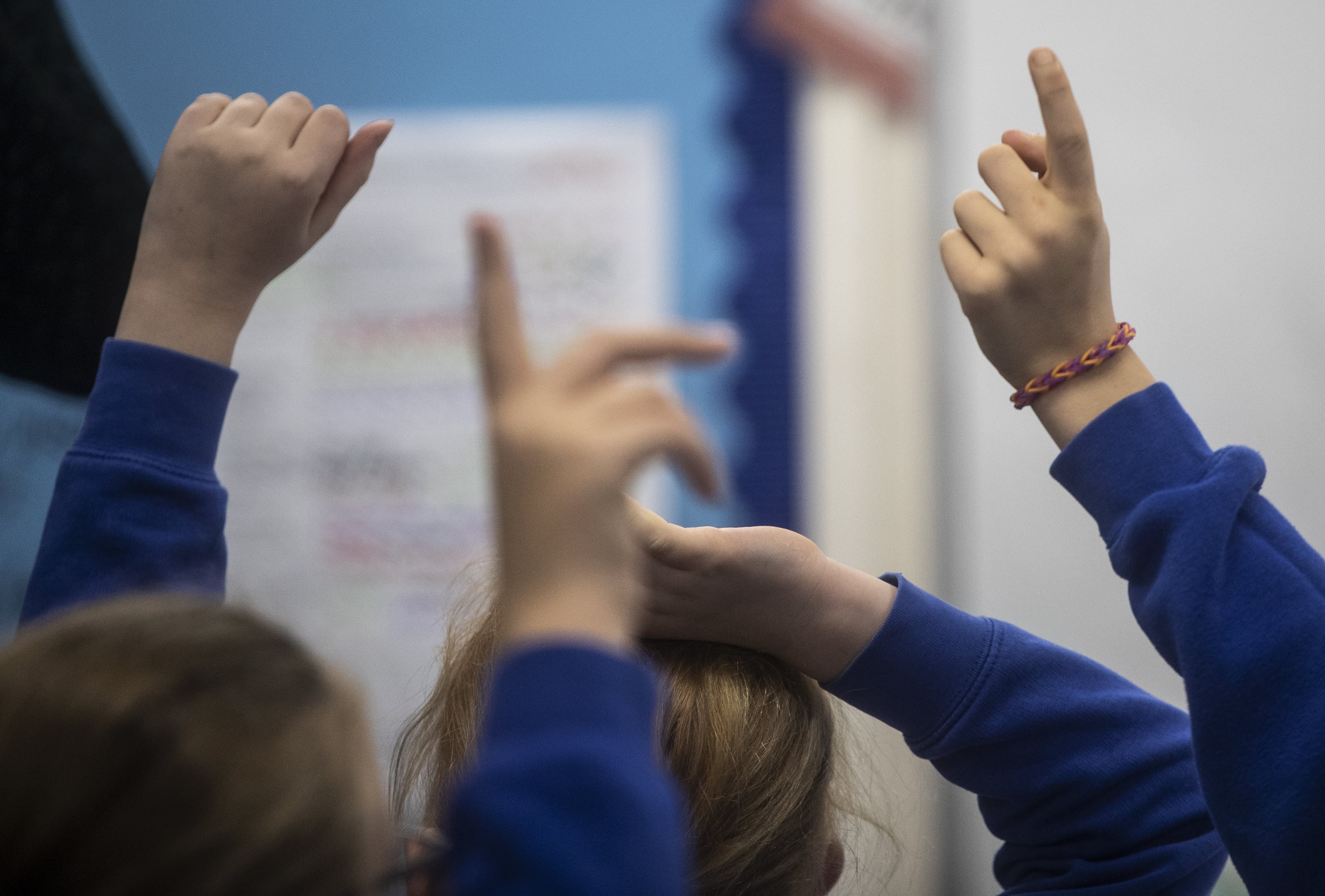 Children’s hands raised in a classroom