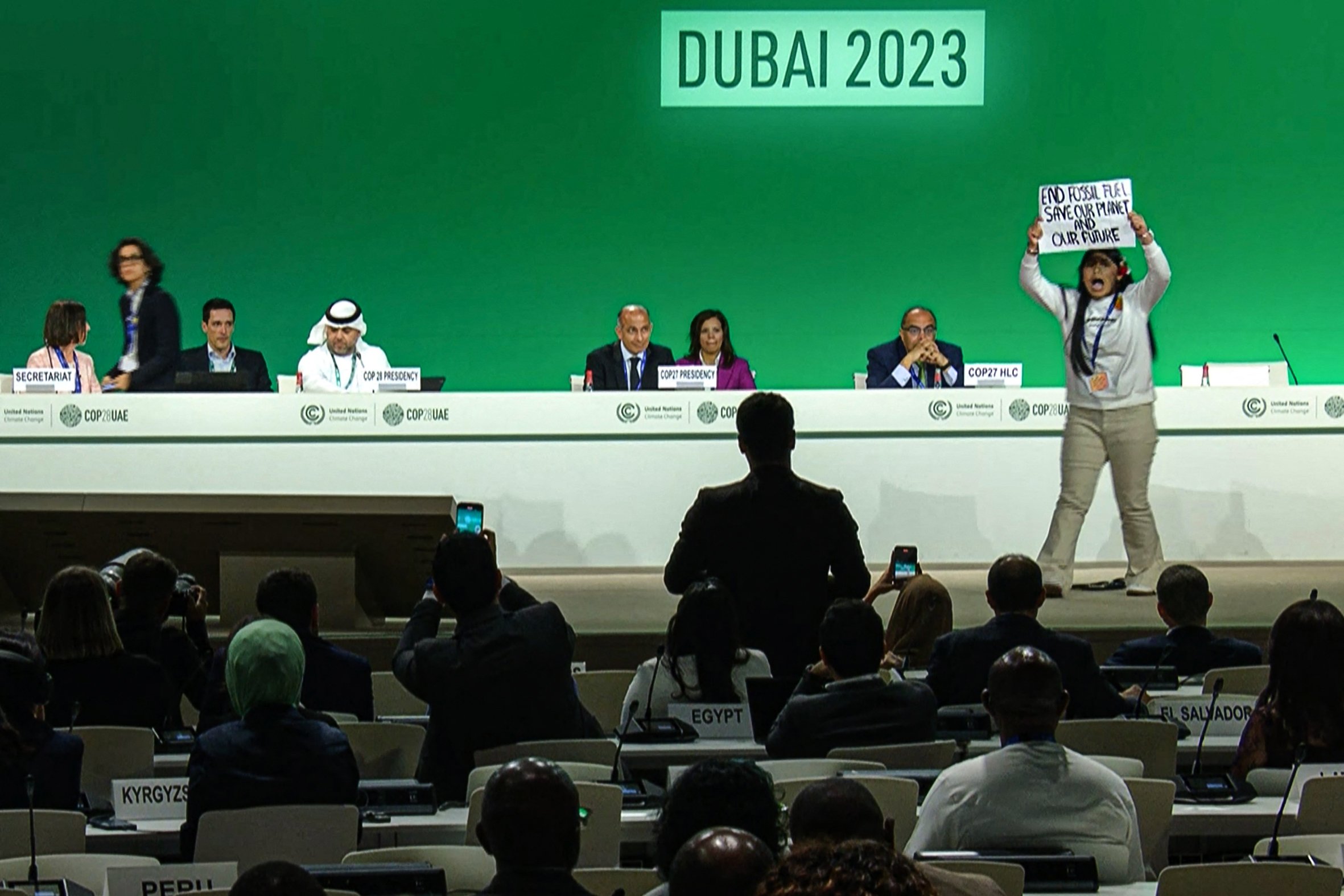 A protester on stage with a sign in their hand.