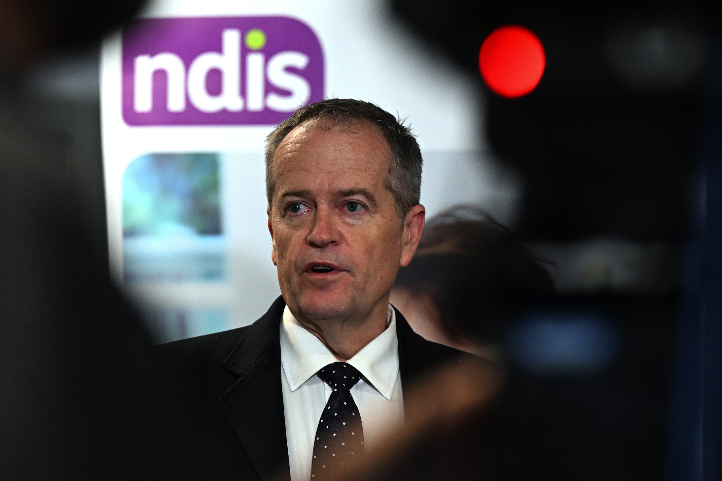 Bill shorten with an NDIS logo behind him.