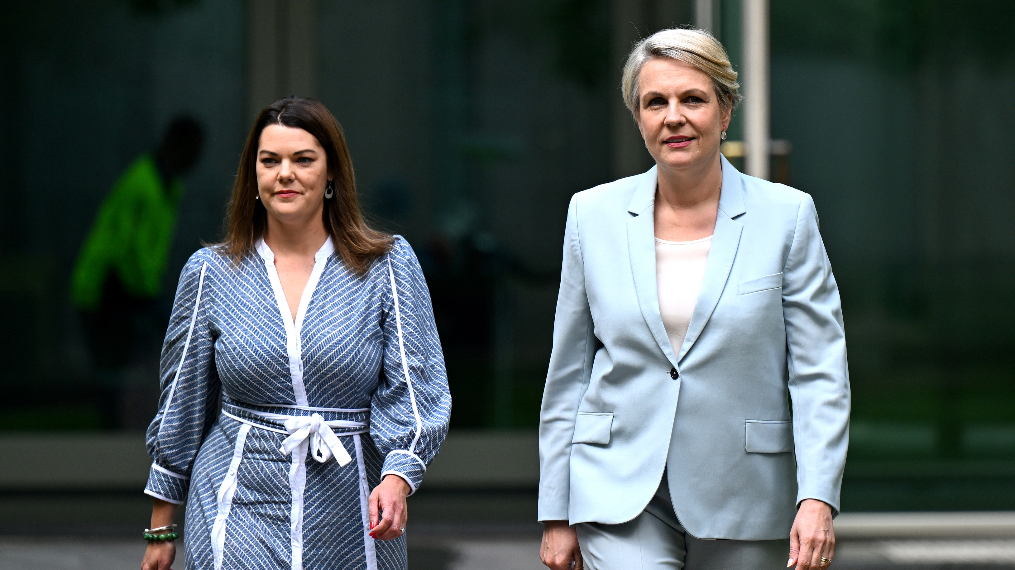 Two women walking beside each another.