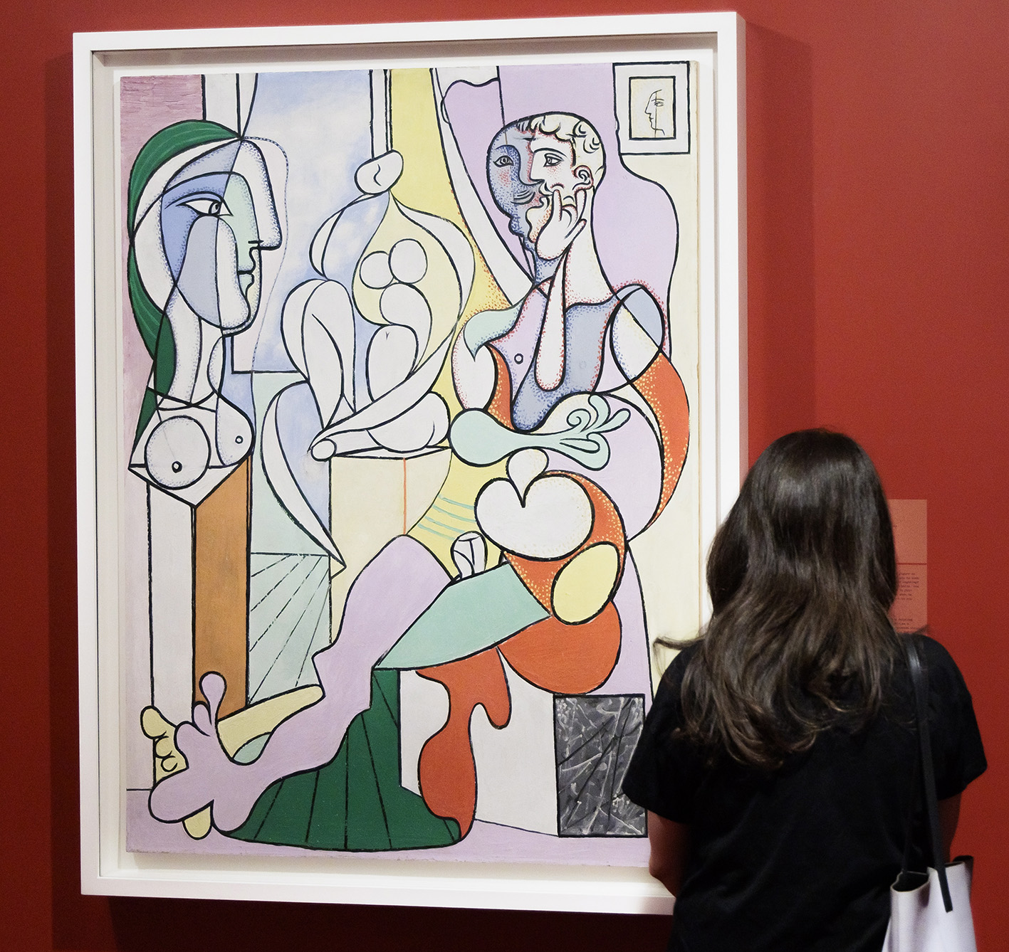 A woman observes a Picasso painting at an art gallery.