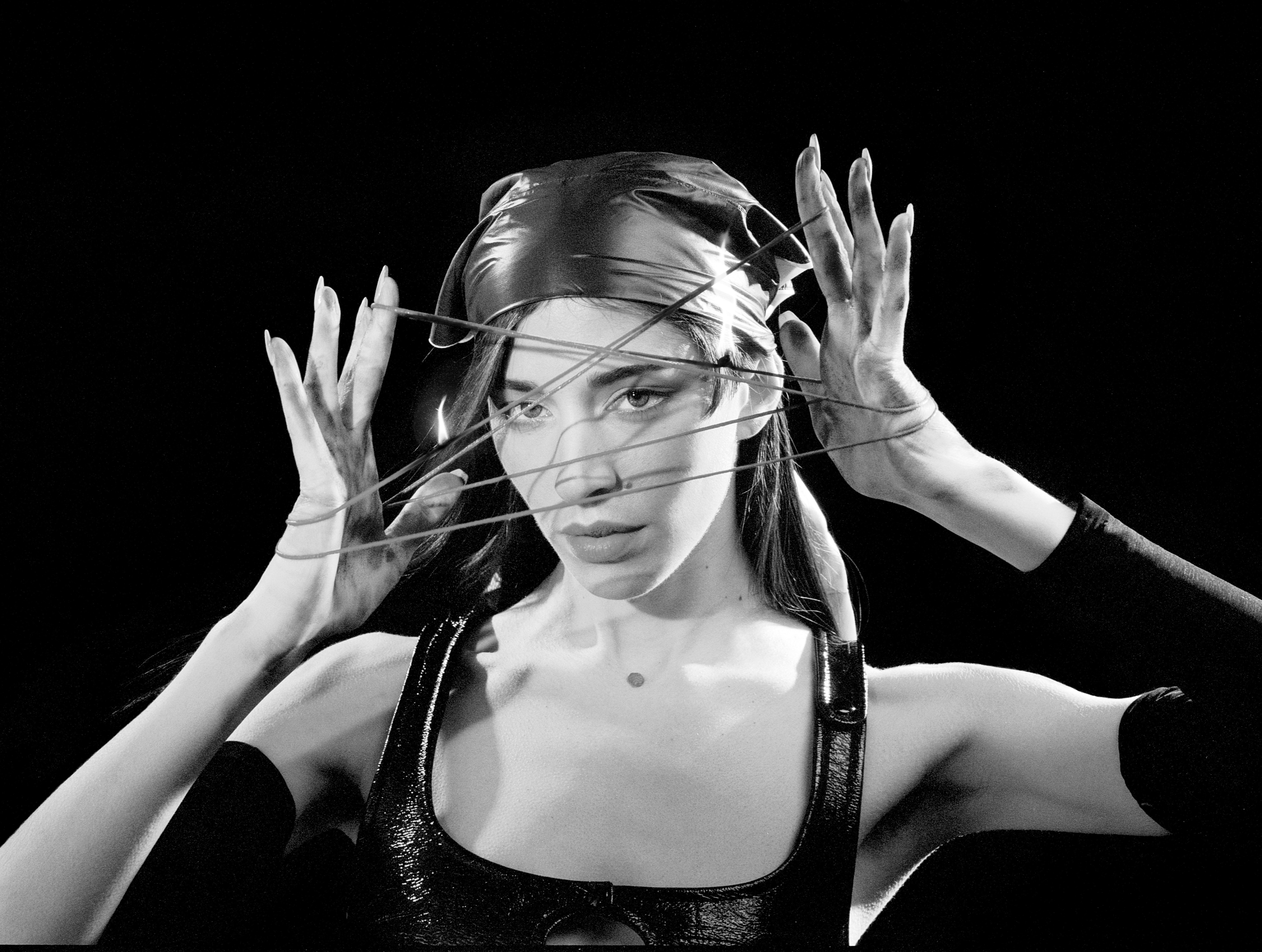 A woman wearing a bandana stretches a thin rope in her hands.