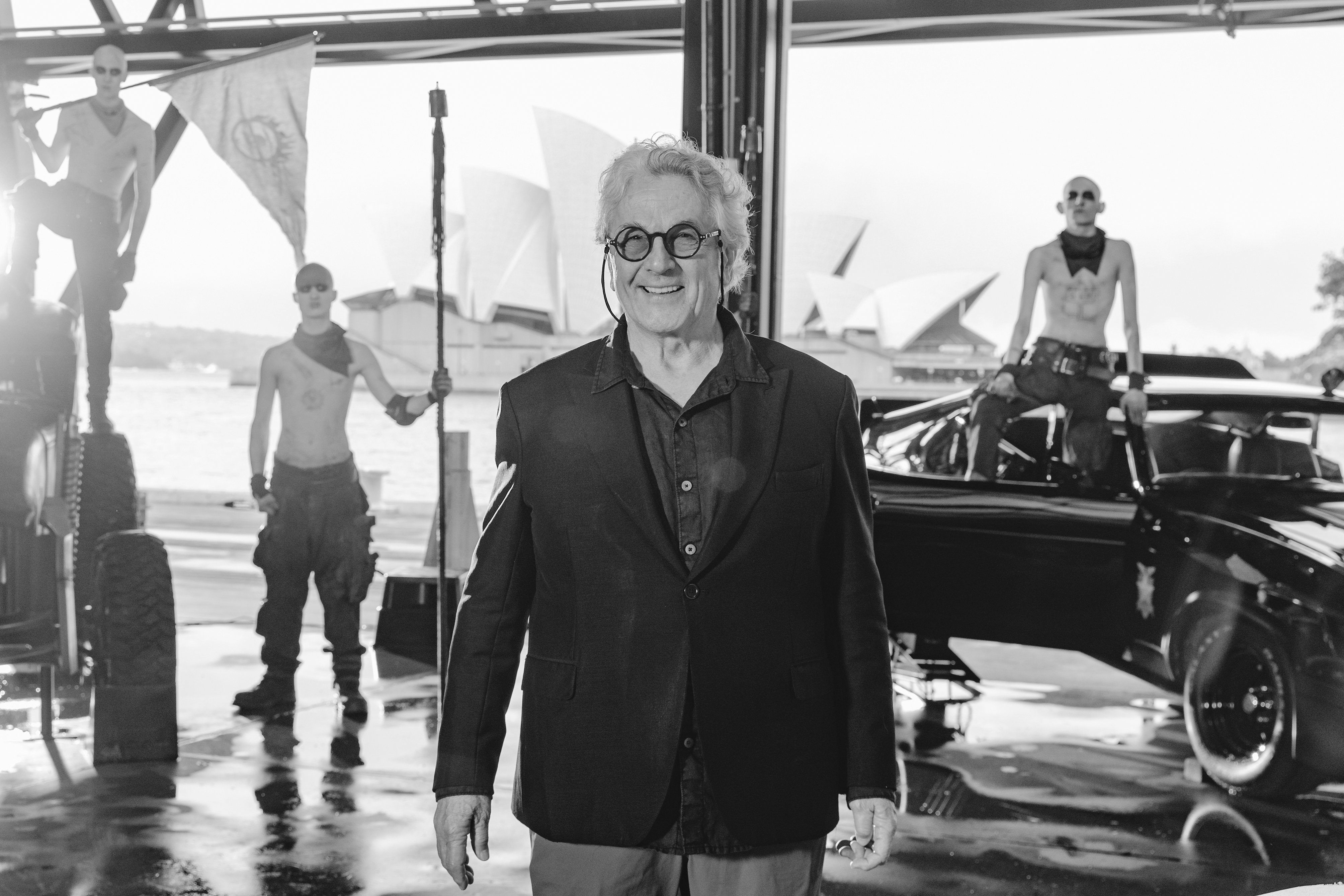 Filmmaker George Miller flanked by Mad Max characters.