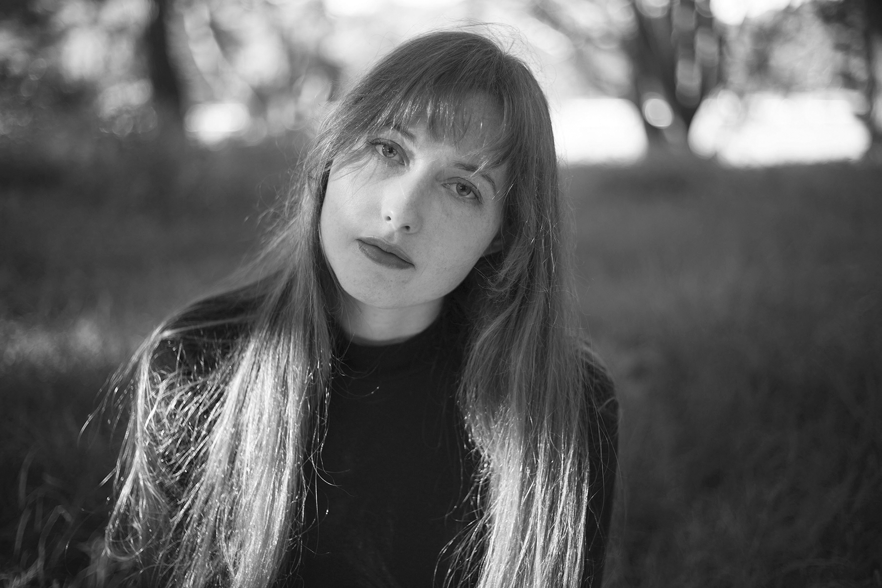 Black and white image of Martha Marlow gazing back at the camera, head tilted.