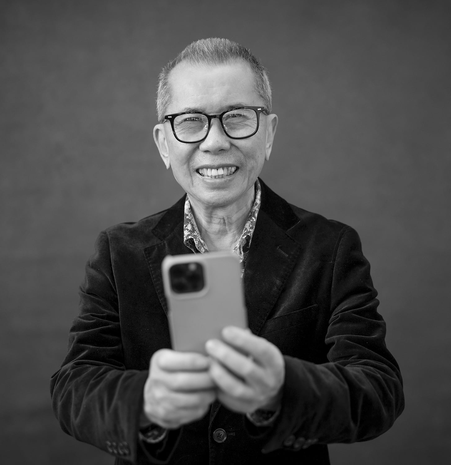 Photographer William Yang holding a phone.