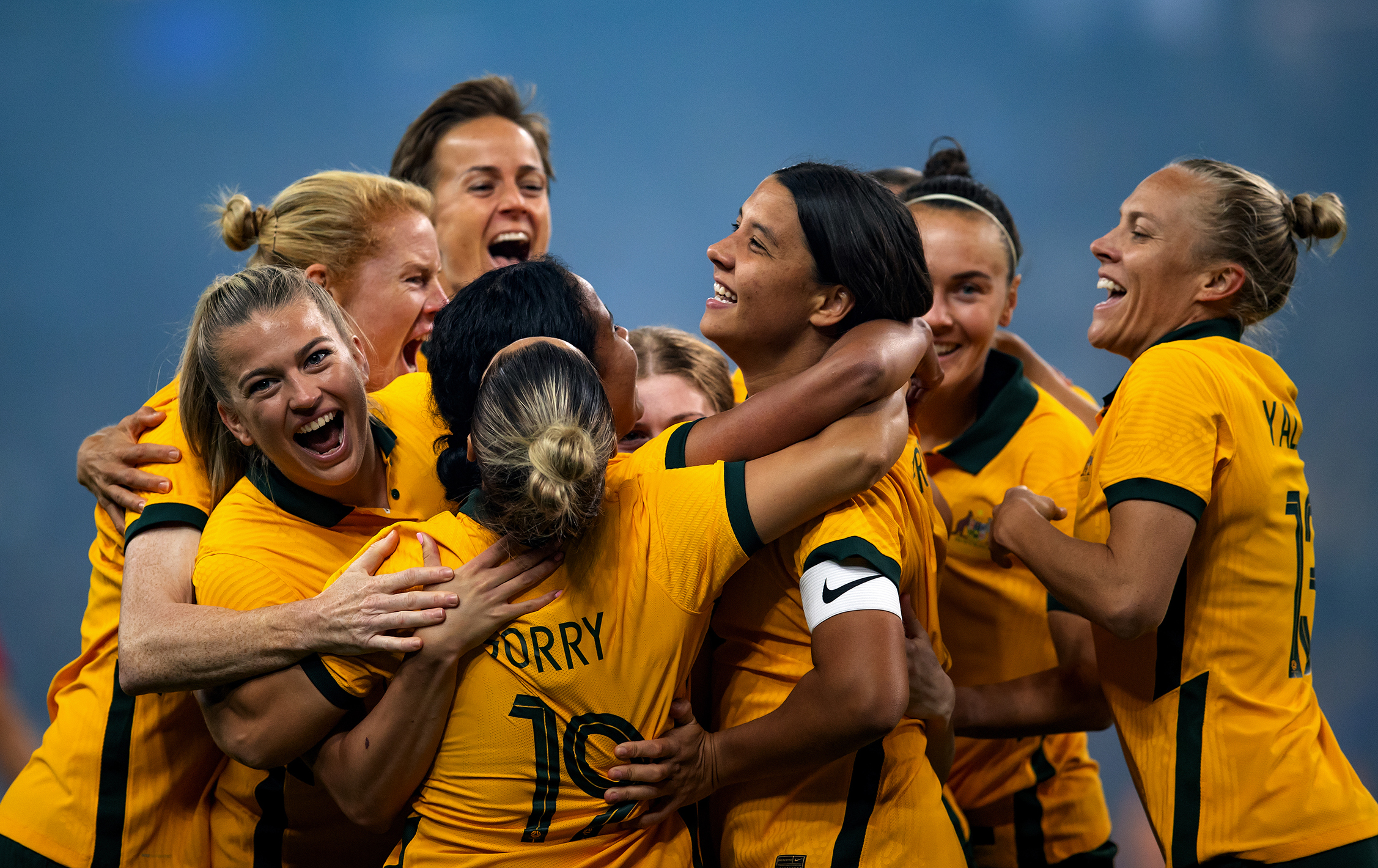 The Matildas hug in celebration.