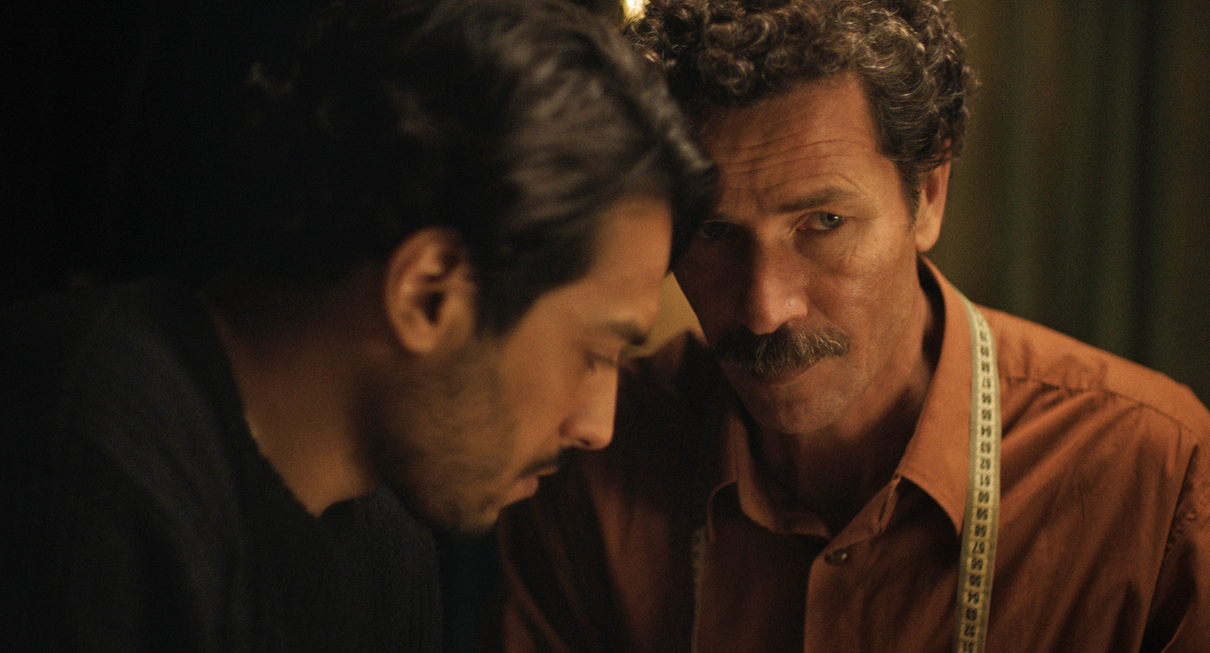 Two men lean toward each other in a scene from The Blue Caftan