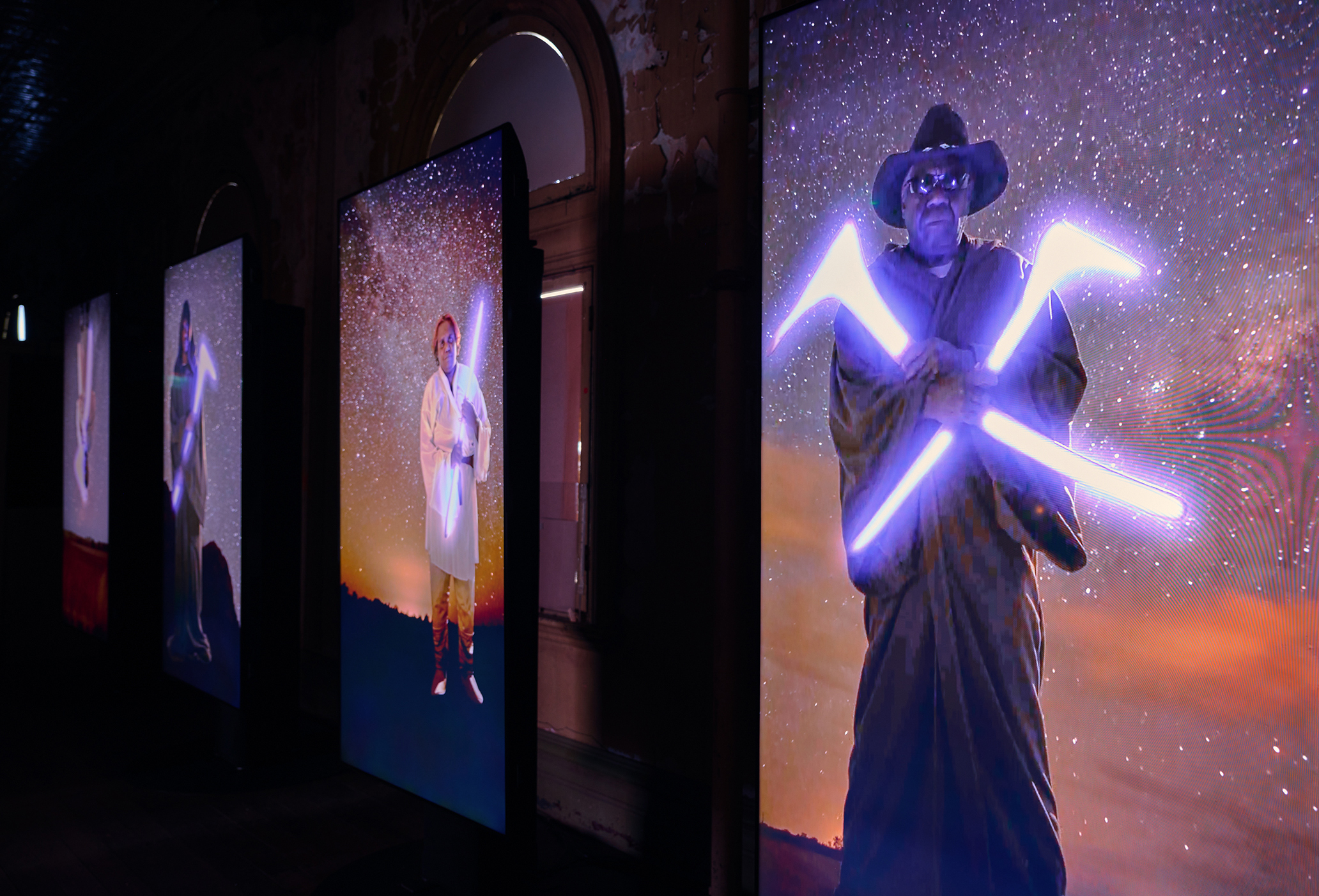 An art installation featuring three panels that show people standing under a starry night with neon-lit tools in their hands.