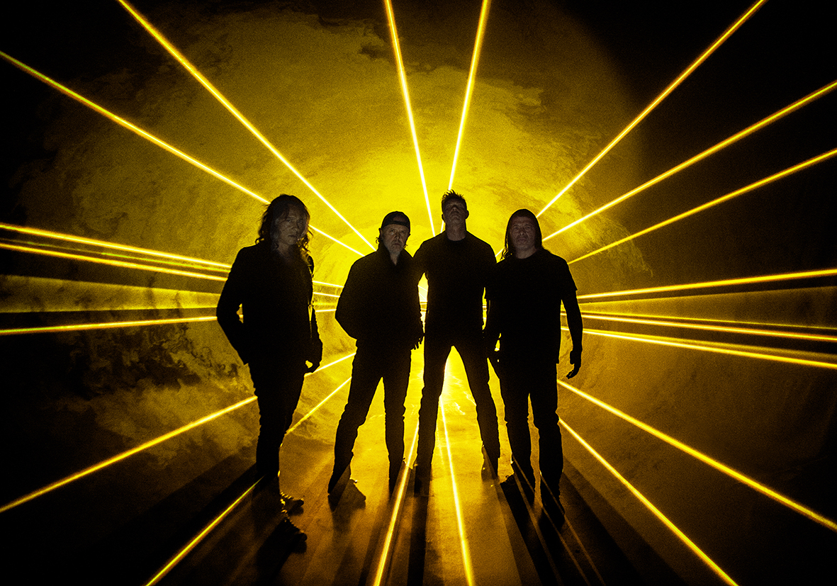 The four members of Metallica stand in front of a yellow light.