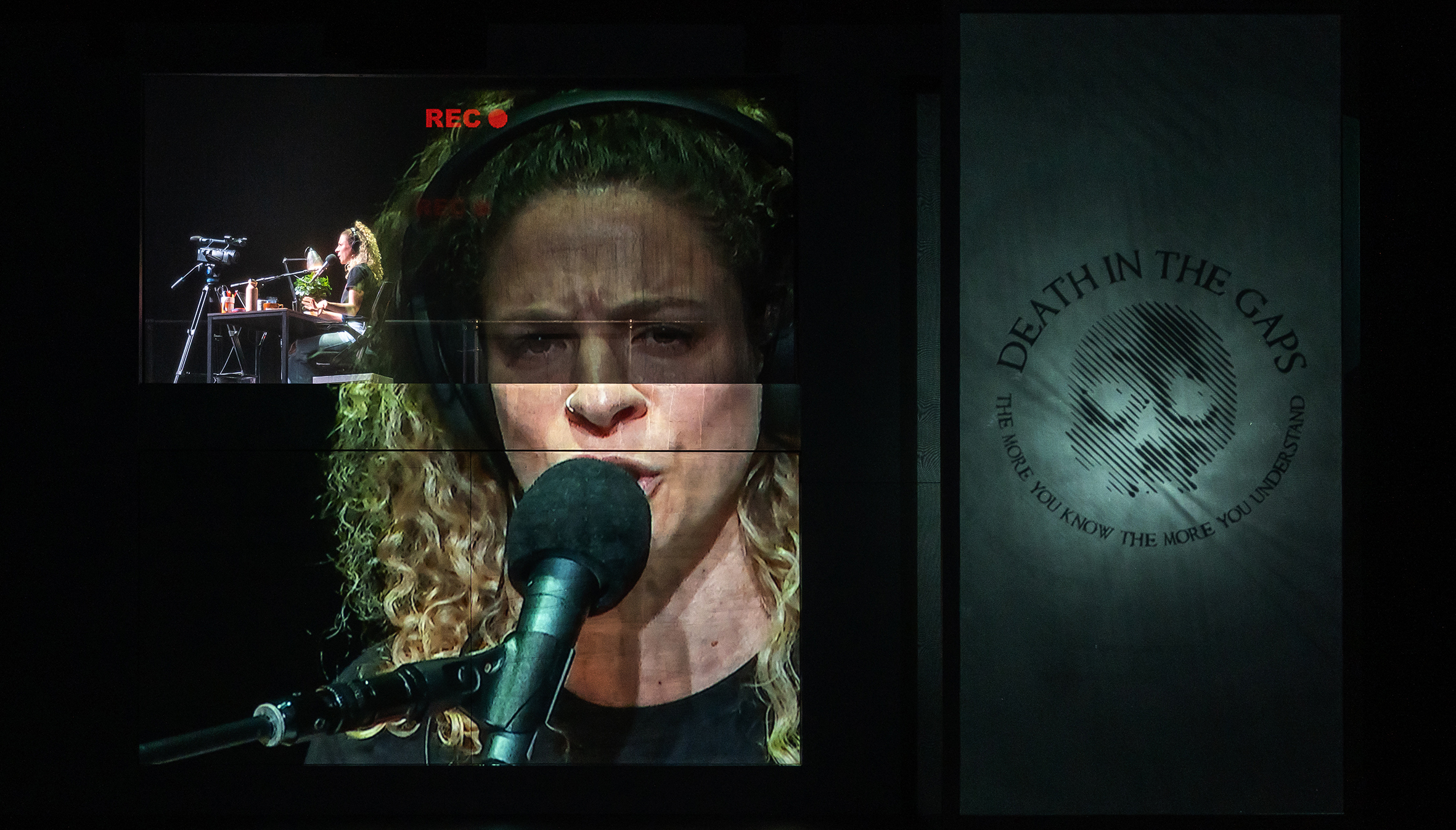 A still from a recording of a performer singing into a microphone.