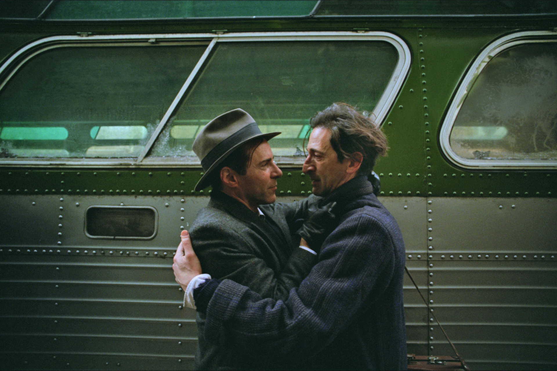 Two men pulled against each other beside a bus.