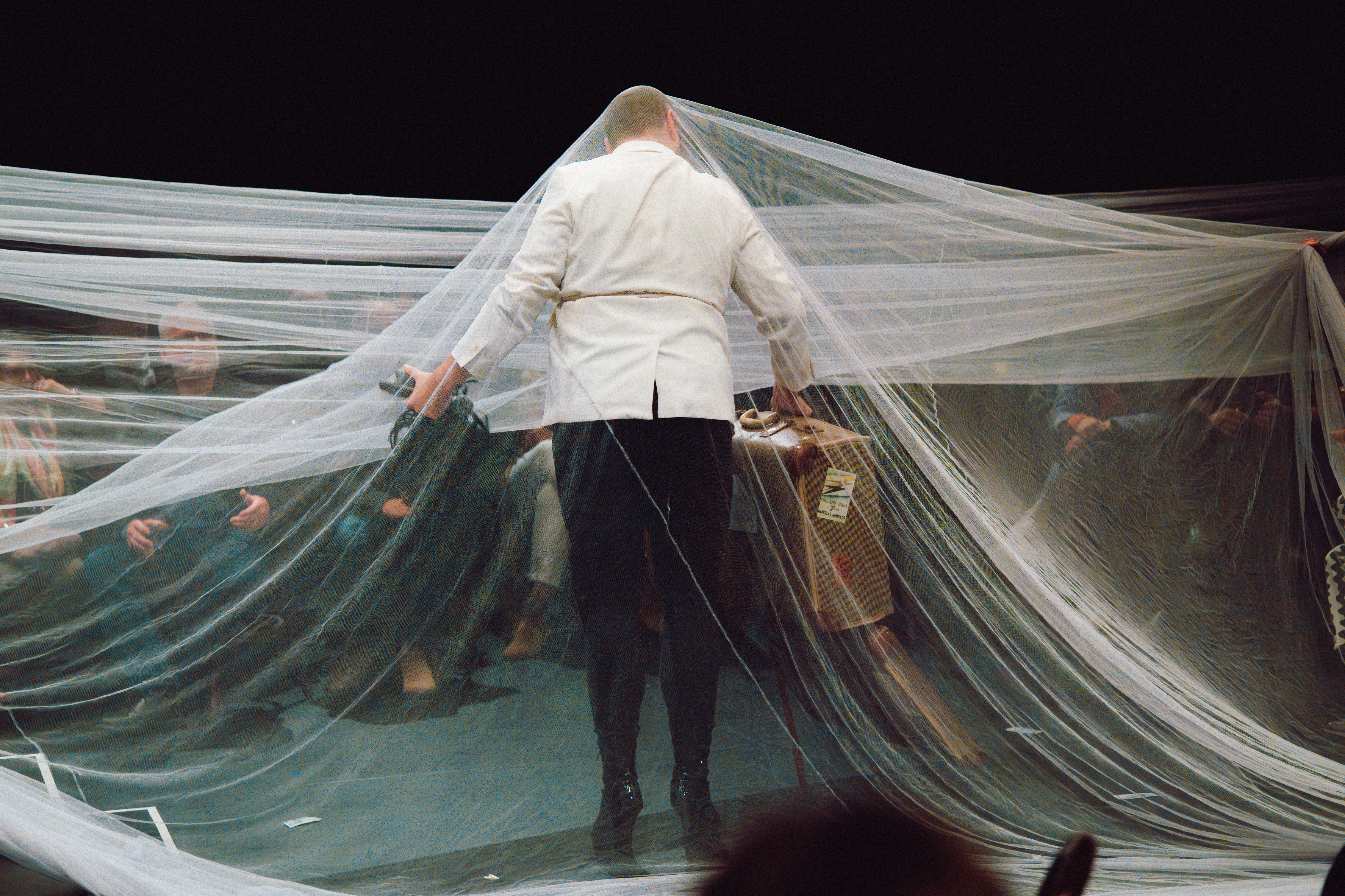 A man stands under a film of white netting, facing an audience in A Slightly Isolated Dog’s Jekyll & Hyde, at the Adelaide Cabaret Festival. 