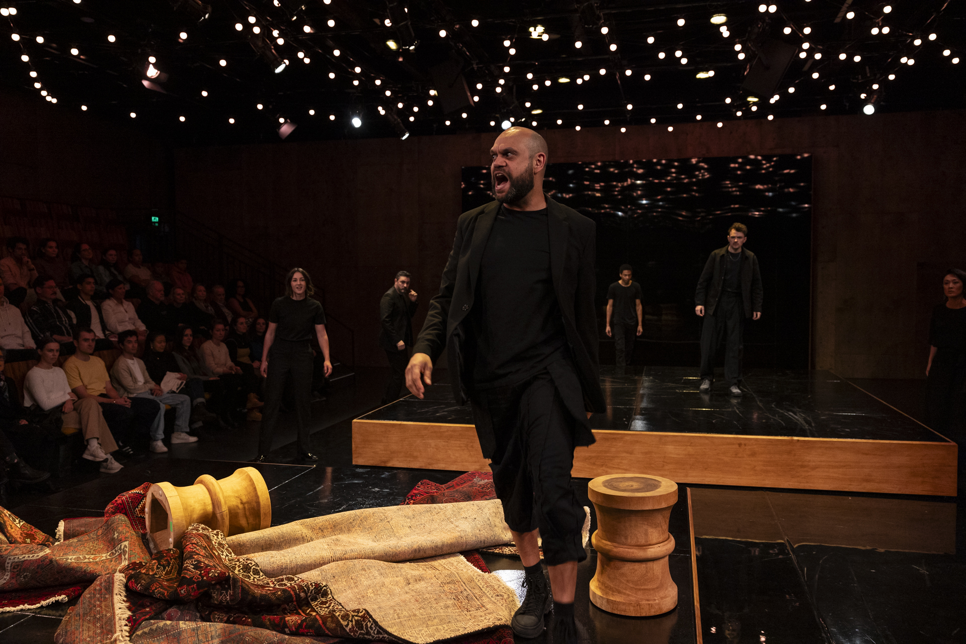 A performer dressed in black on stage before an audience.