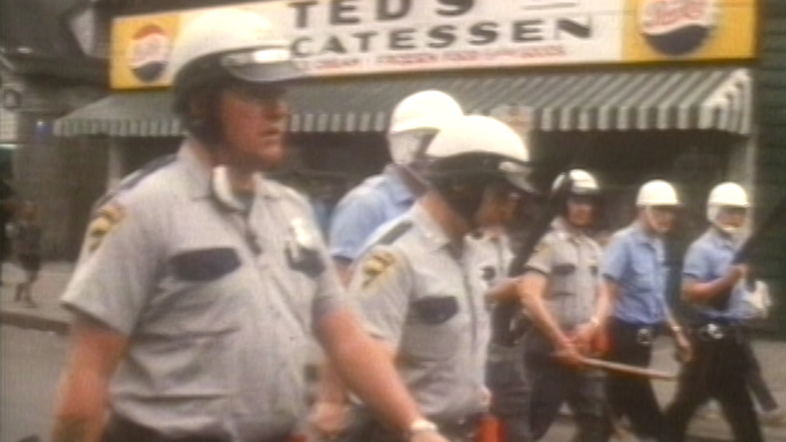 A line of police officers holding batons.