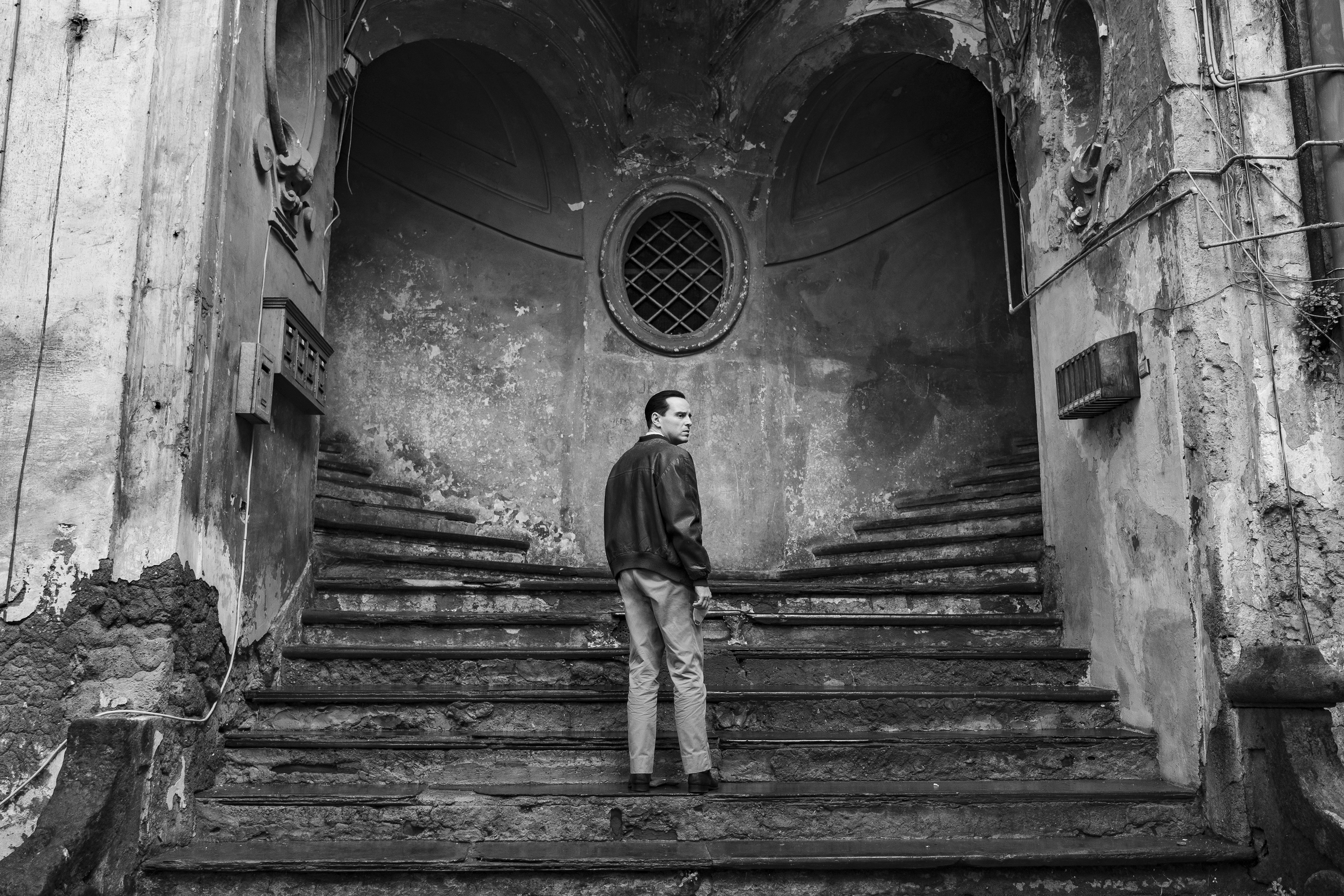 Andrew Scott on the steps of an old Italian building.