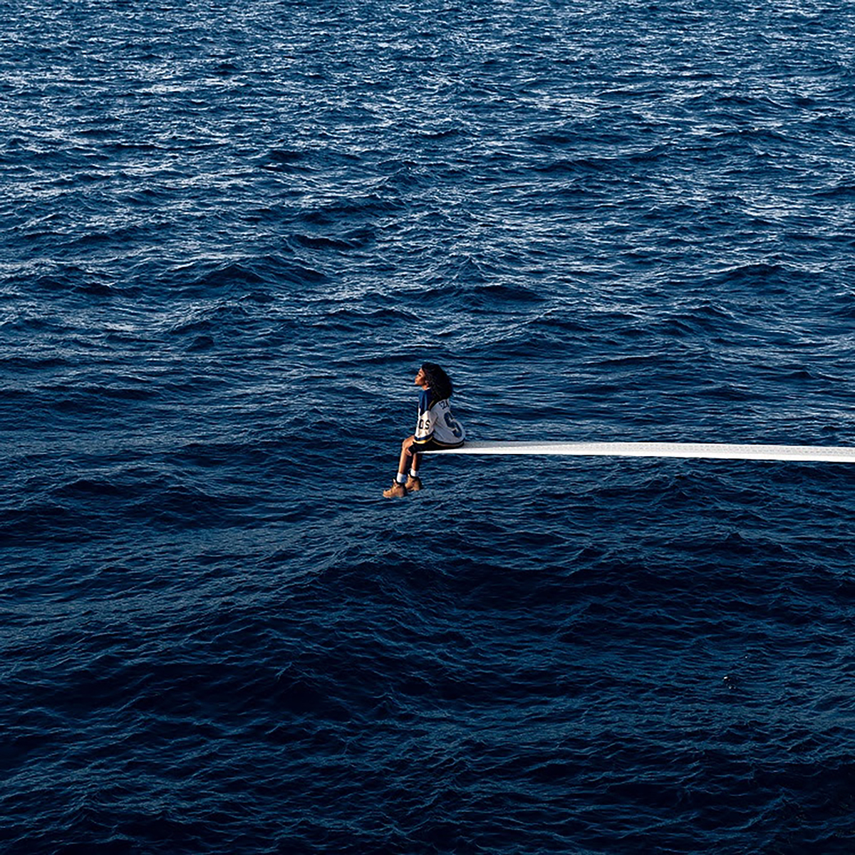 A woman sitting on the end of a diving board.