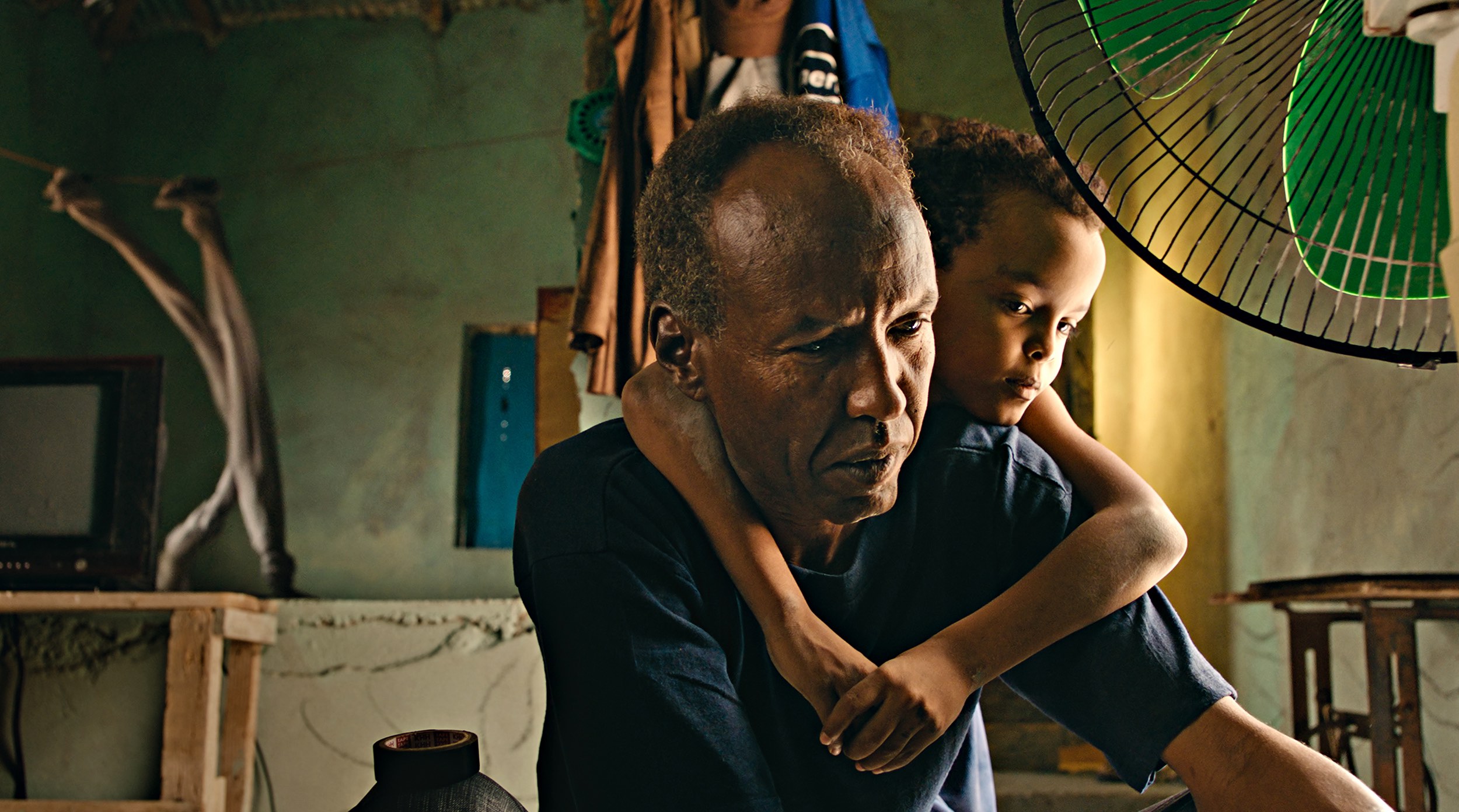 A young boy with his arms wrapped around the shoulders of a man.