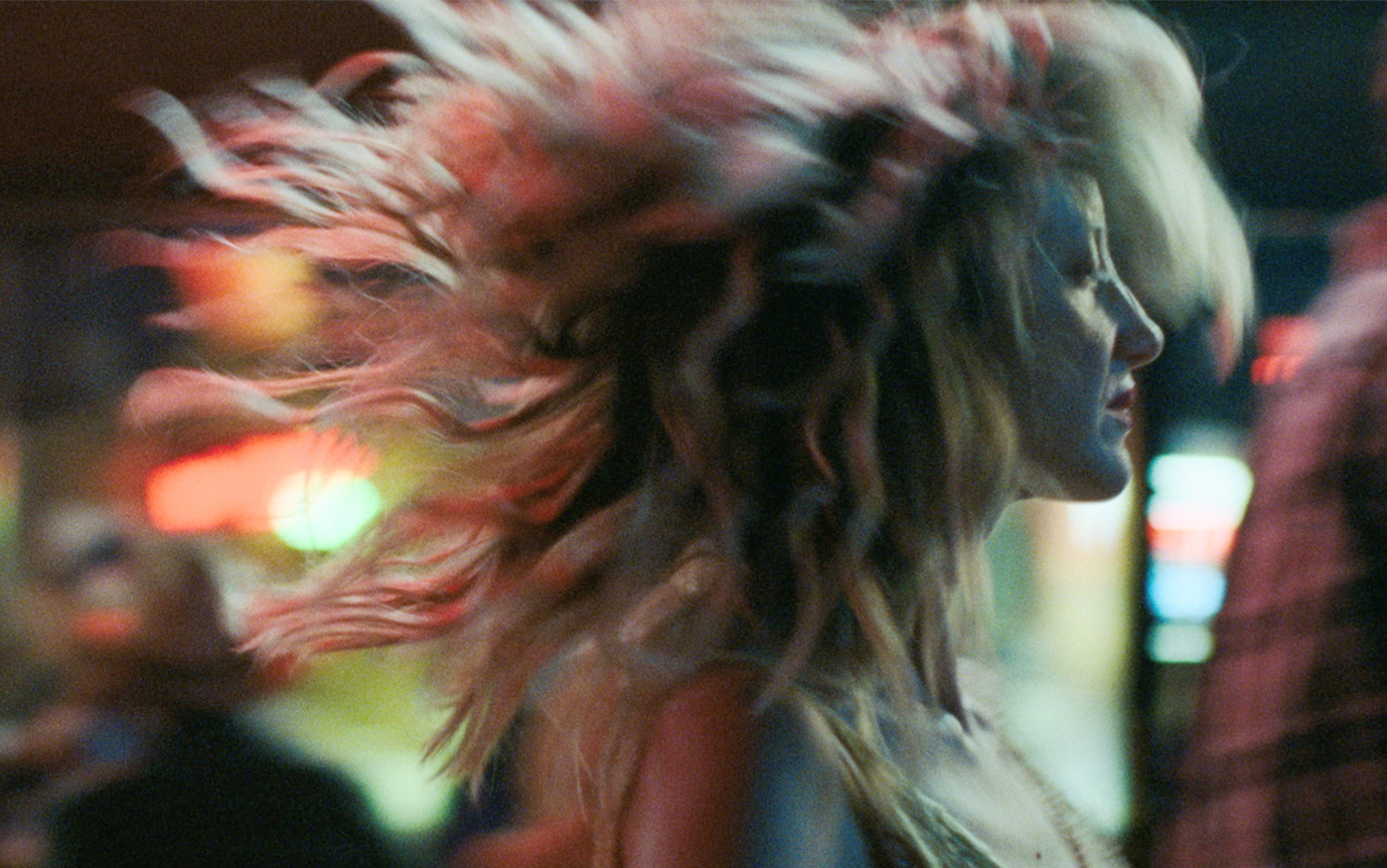 A close-up of Andrea Riseborough dancing, her hair suspended in the air.