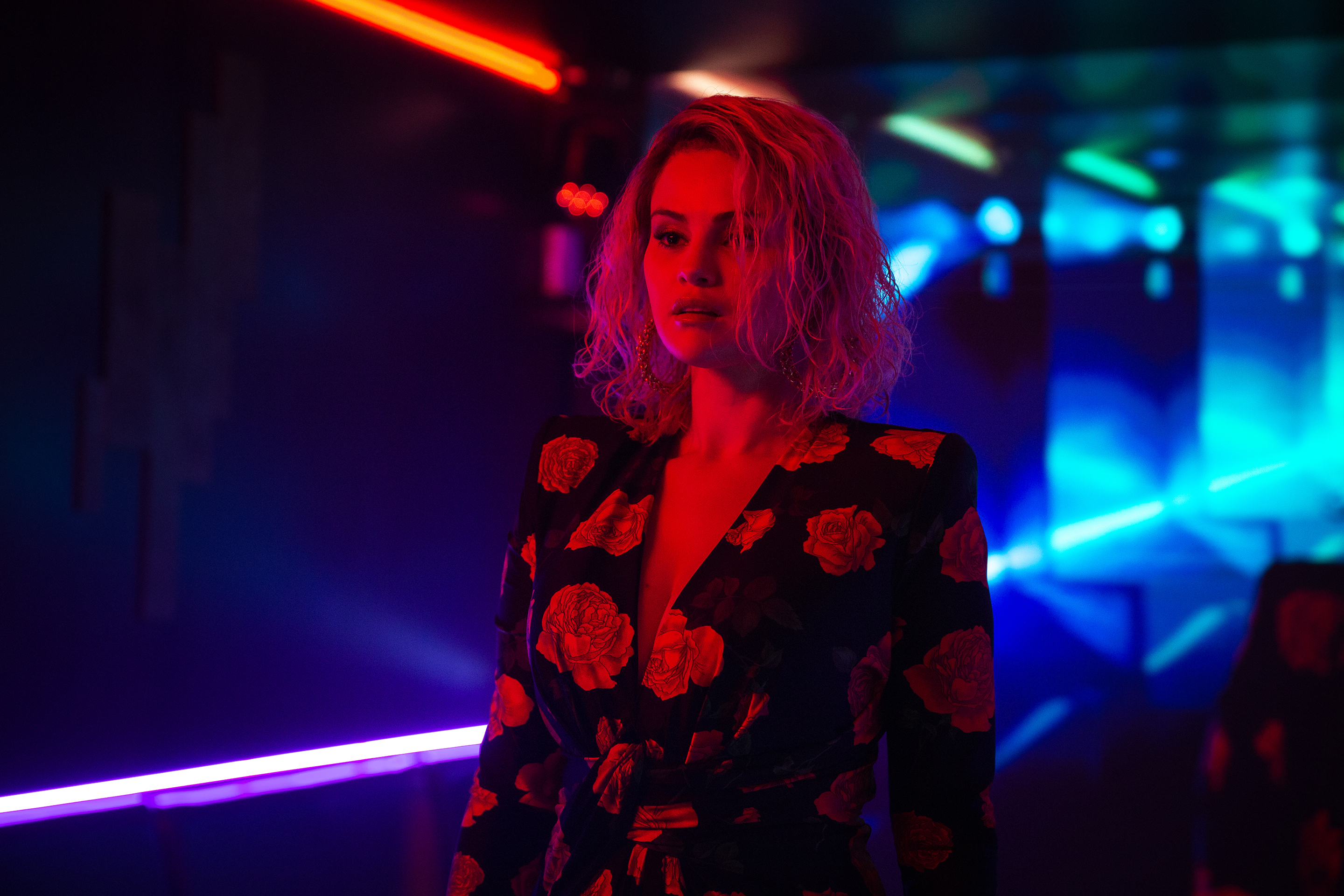 Selena Gomez under red lights in a scene from Emilia Perez.