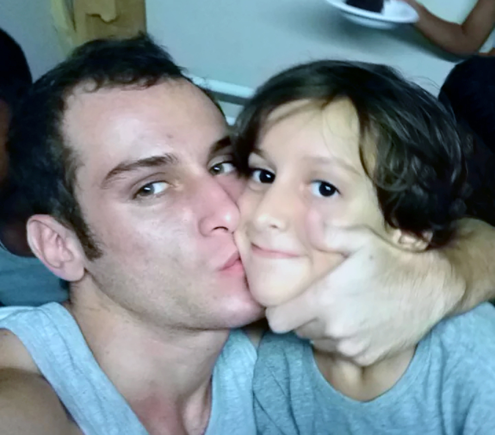A young man embraces his child brother.